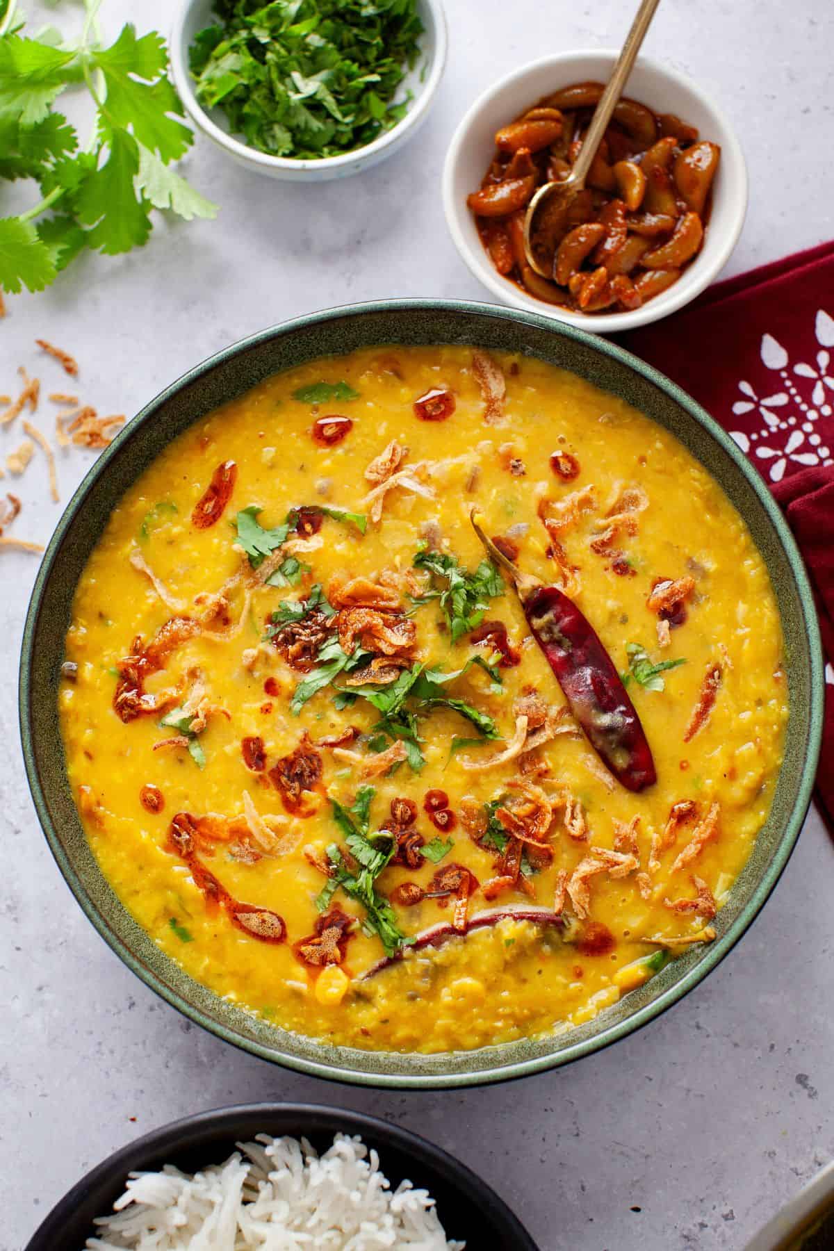 Dal Tadka served in a green bowl with tempering, cilantro and fried onions.