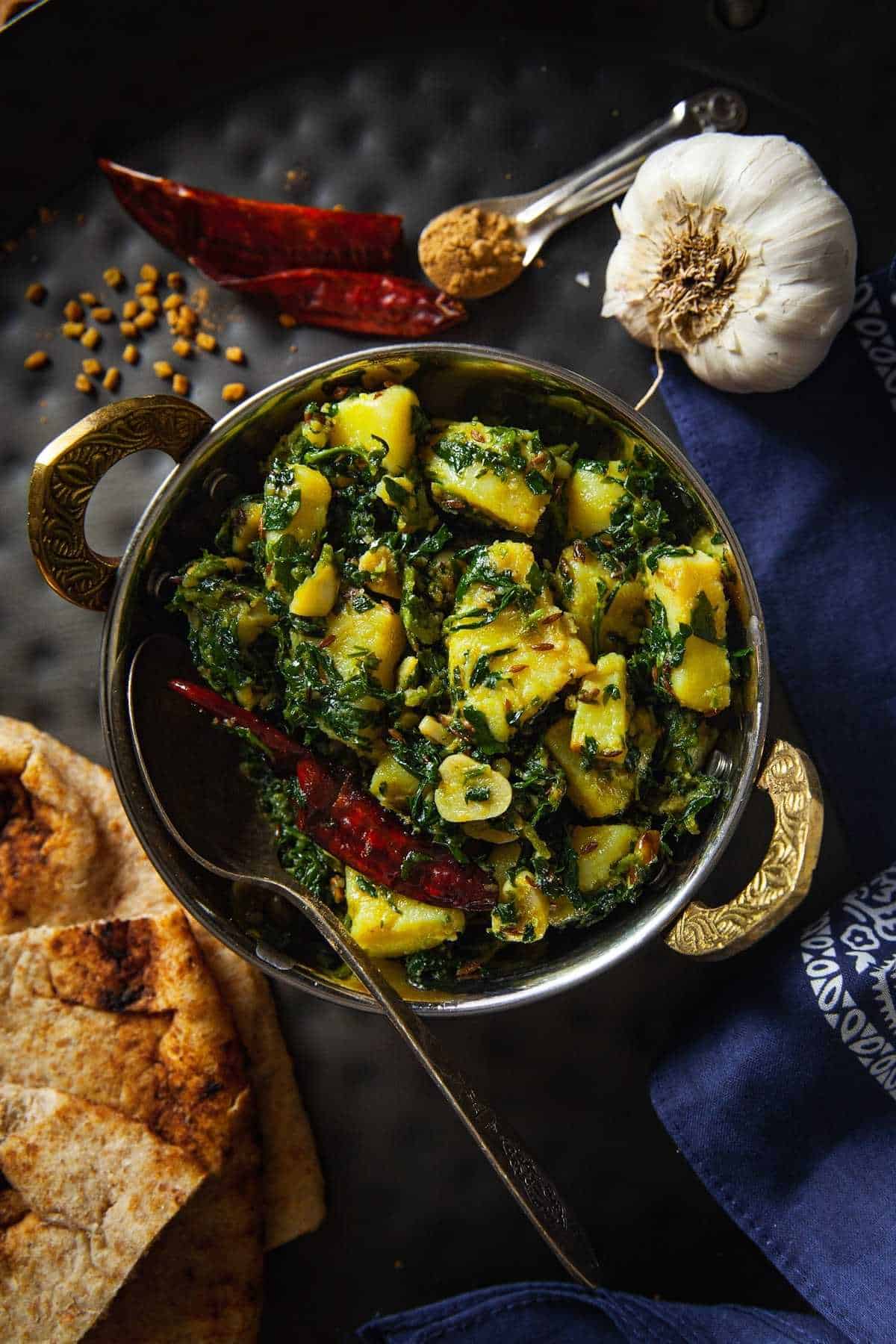 Aloo Methi Sabji served in a stainless steel indian kadai with spices. 