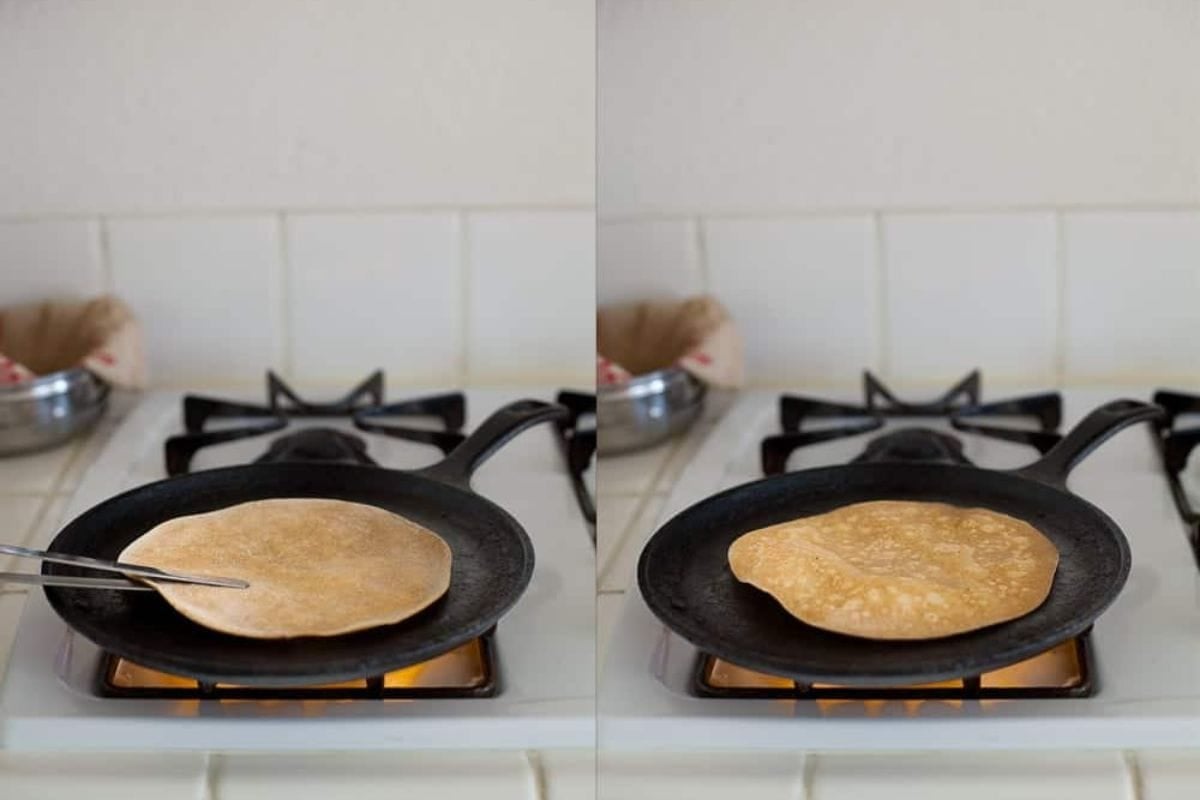 Roti is being flipped on the hot iron tawa.