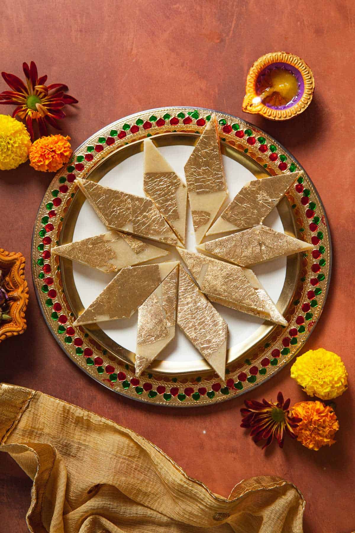 Kaju Katli on a colorful plate with flowers and diya.