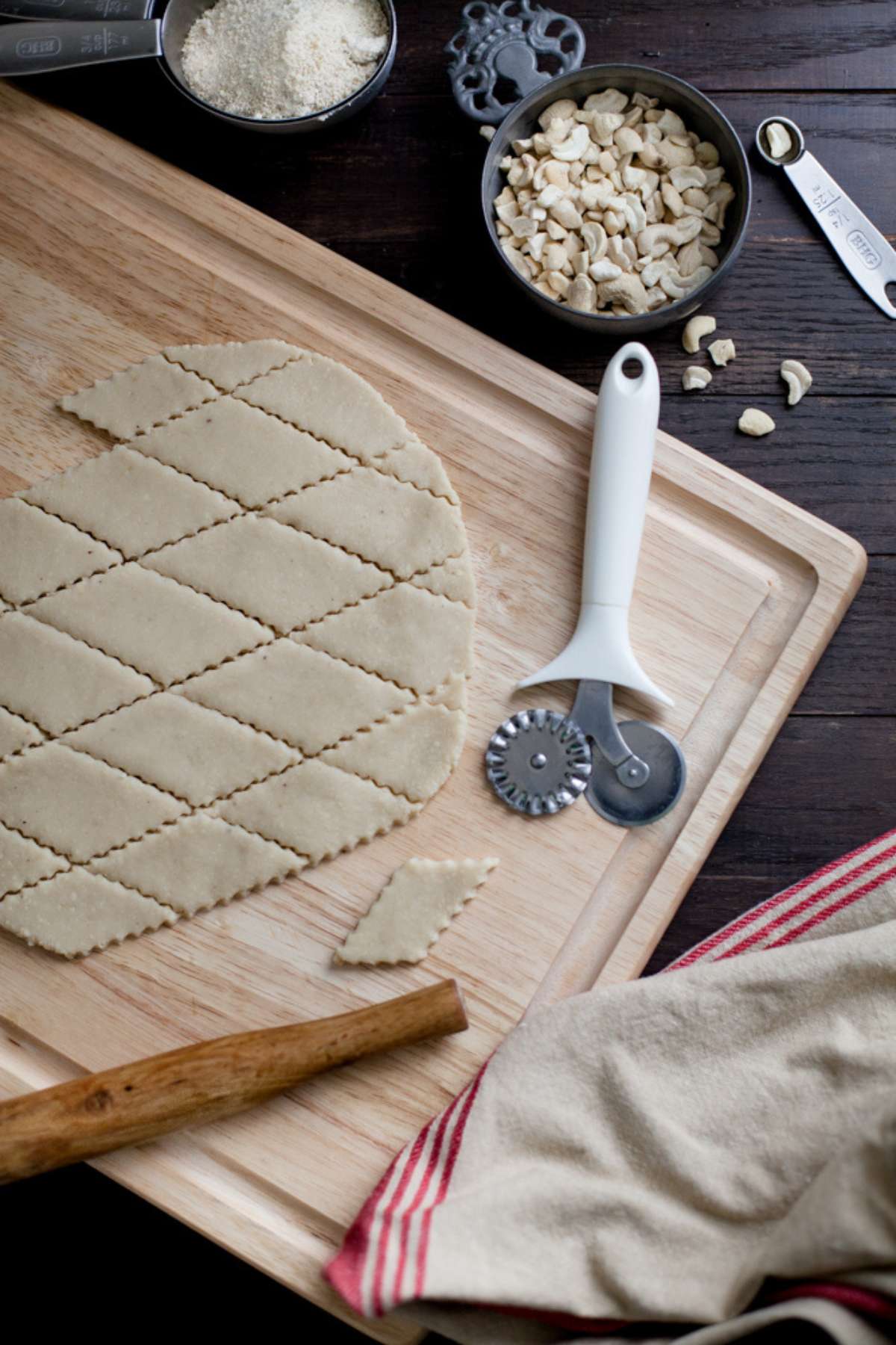 Cutting rolled out kaju katli dough with a ravioli cutter.