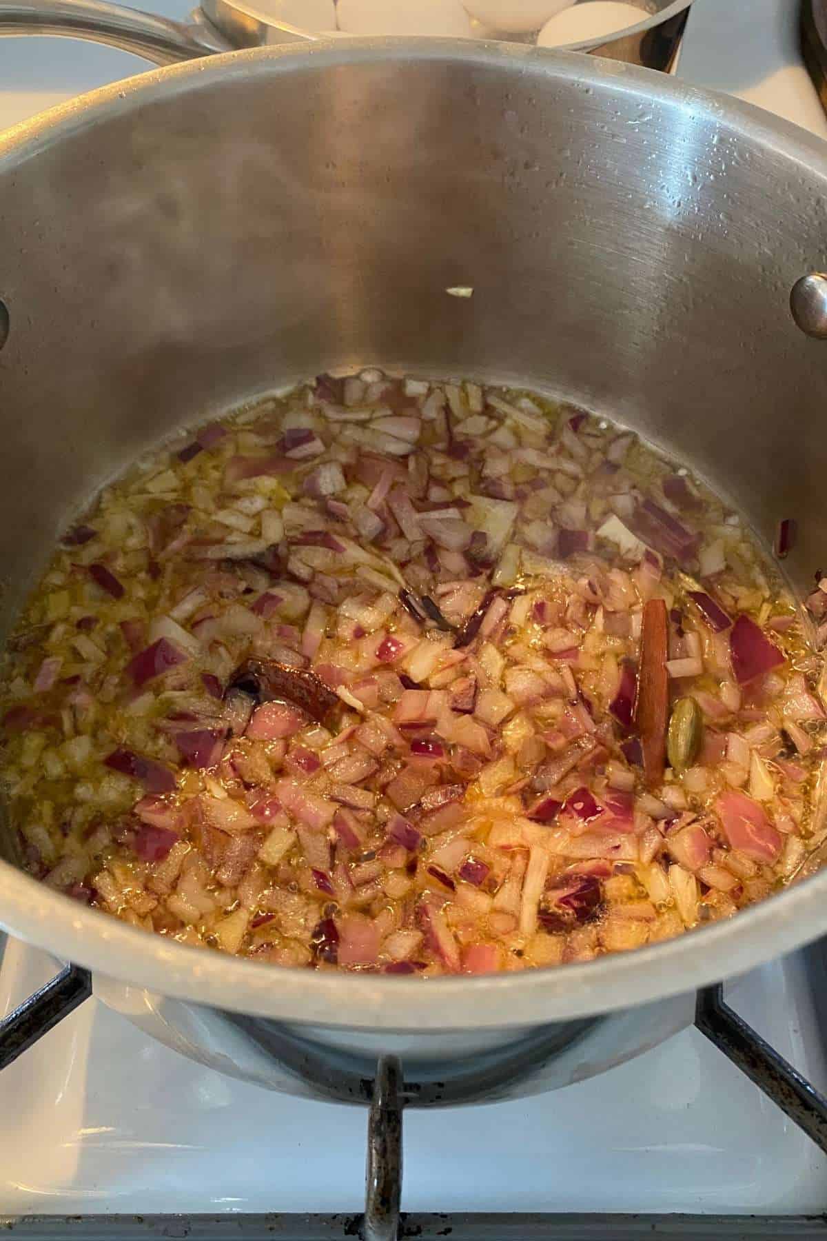 Onions and whole spices growing in oil.