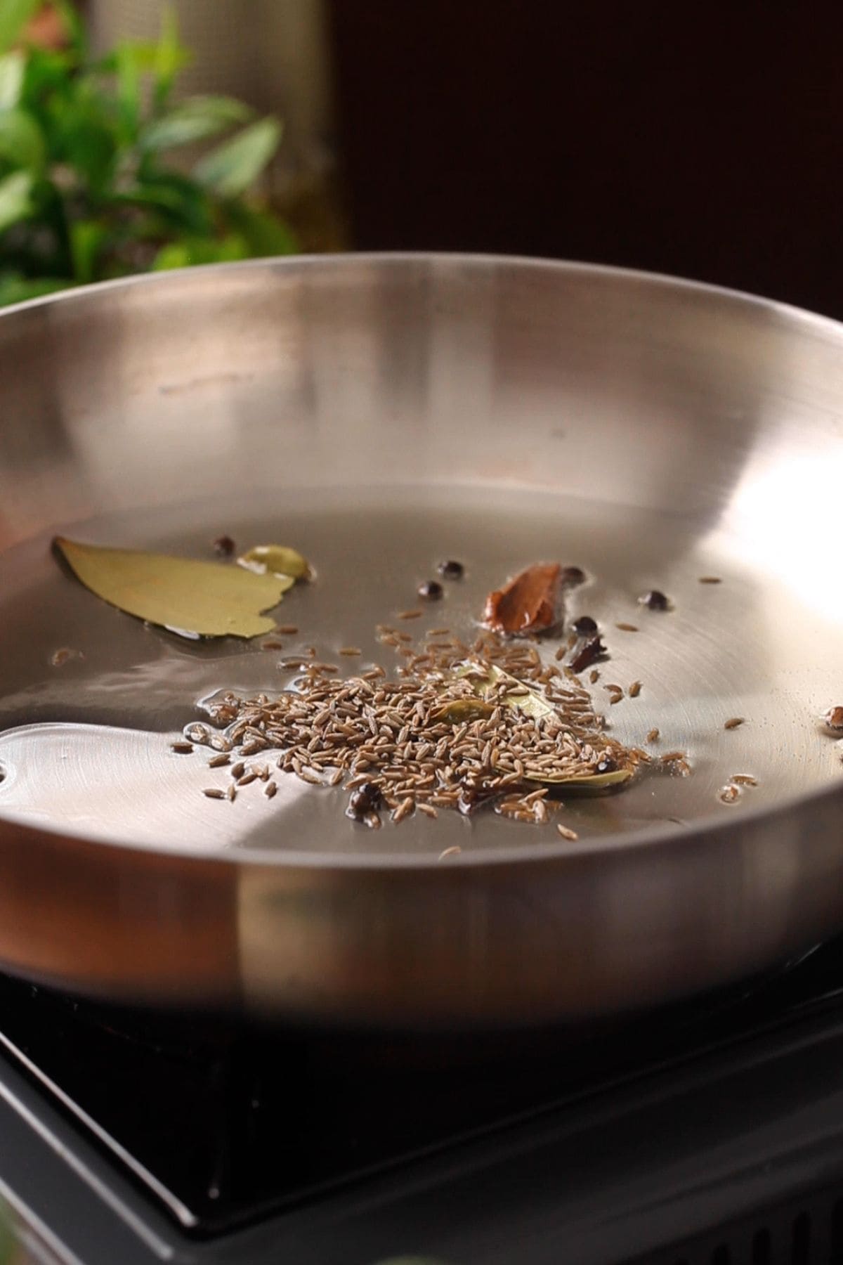 Oil in a stainless steel skillet tempered with whole spices.