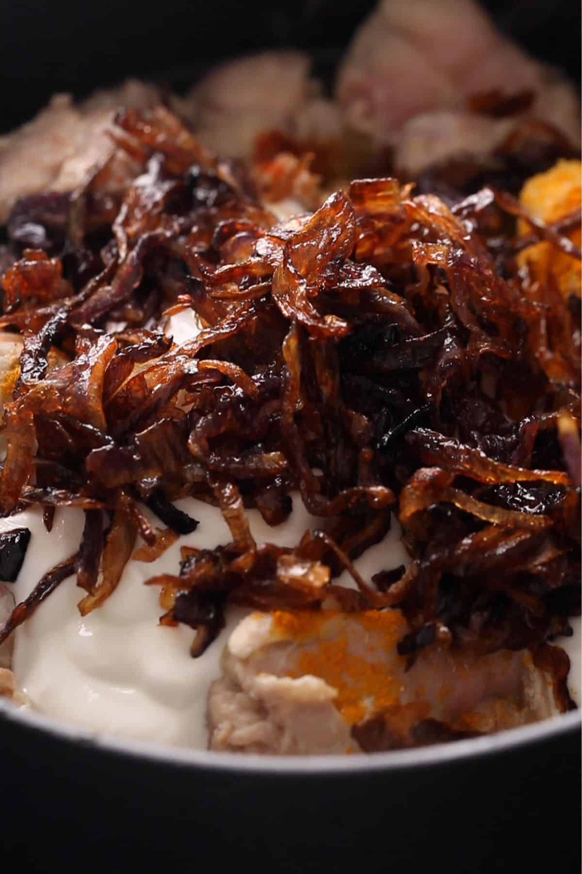 Spices, yogurt and fried onions are added to the chicken next.