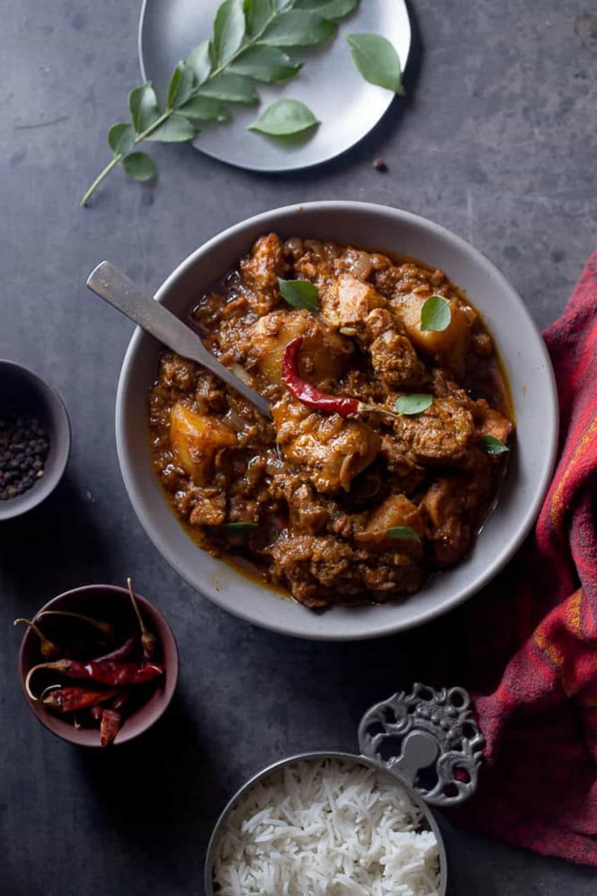 Chicken Vindaloo served in a grey bowl with steamed basmati rice on side.