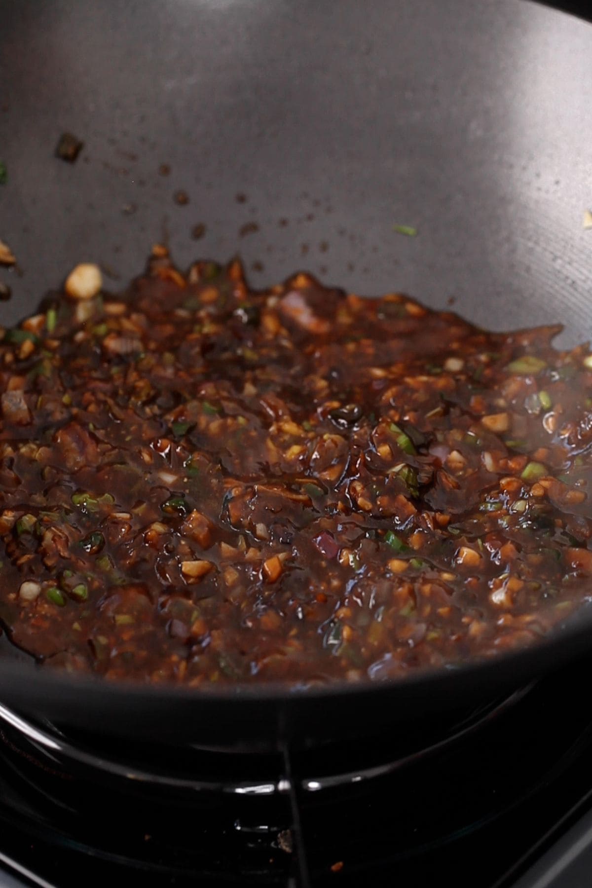 The sauce is bubbling in a black wok.
