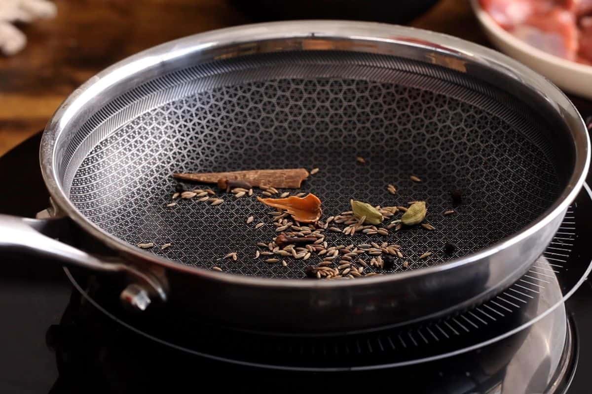 Roasting whole spices in a black skillet.