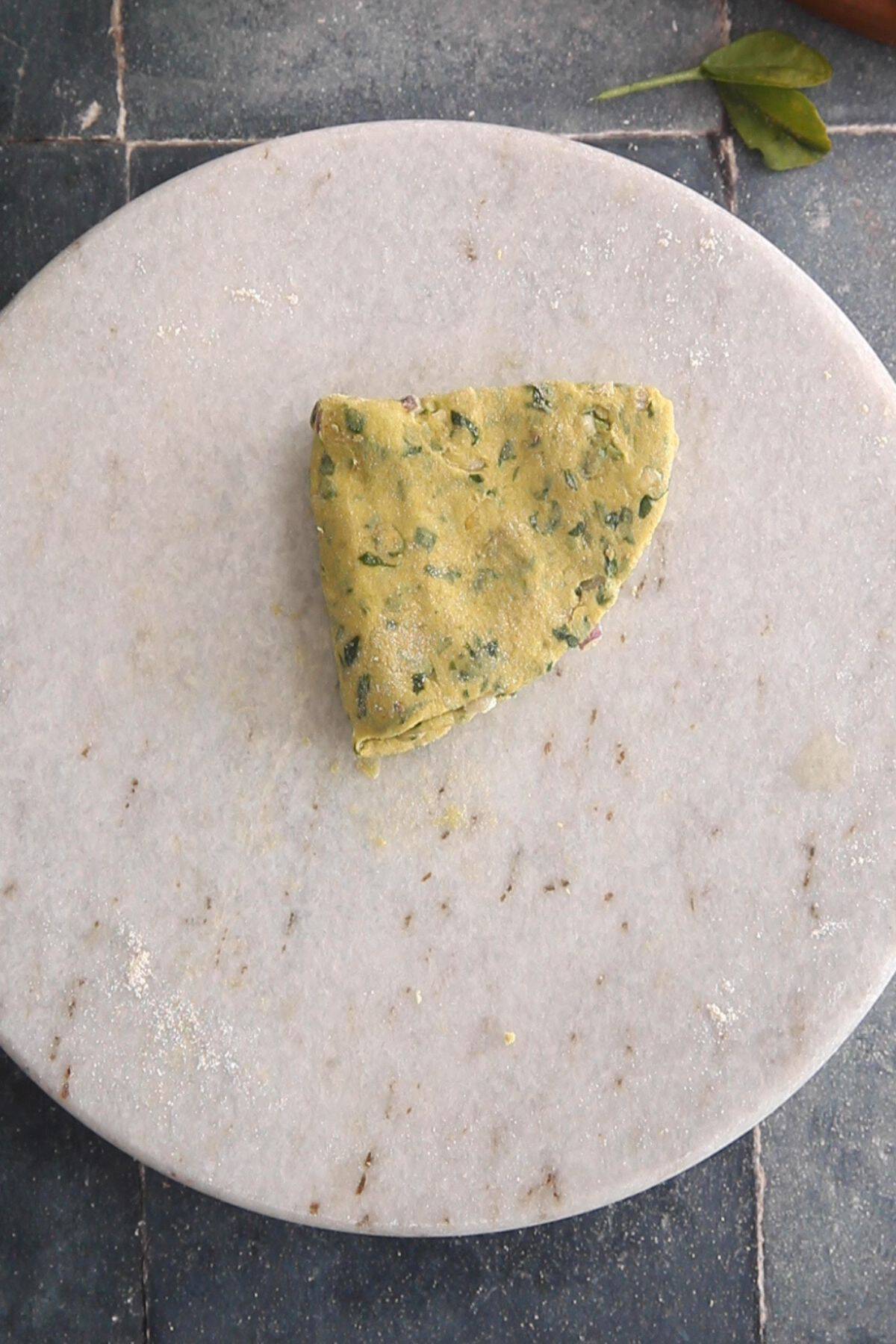 Rolled dough is folded over again to create a triangle shape. 