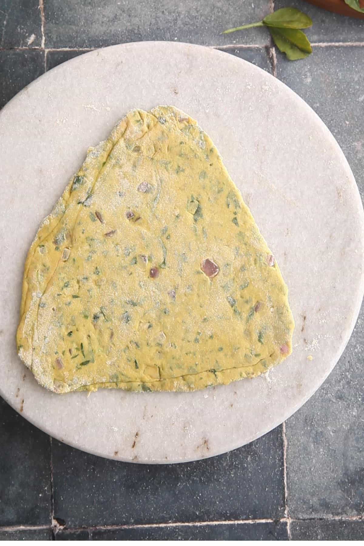 Triangle methi paratha is rolled.