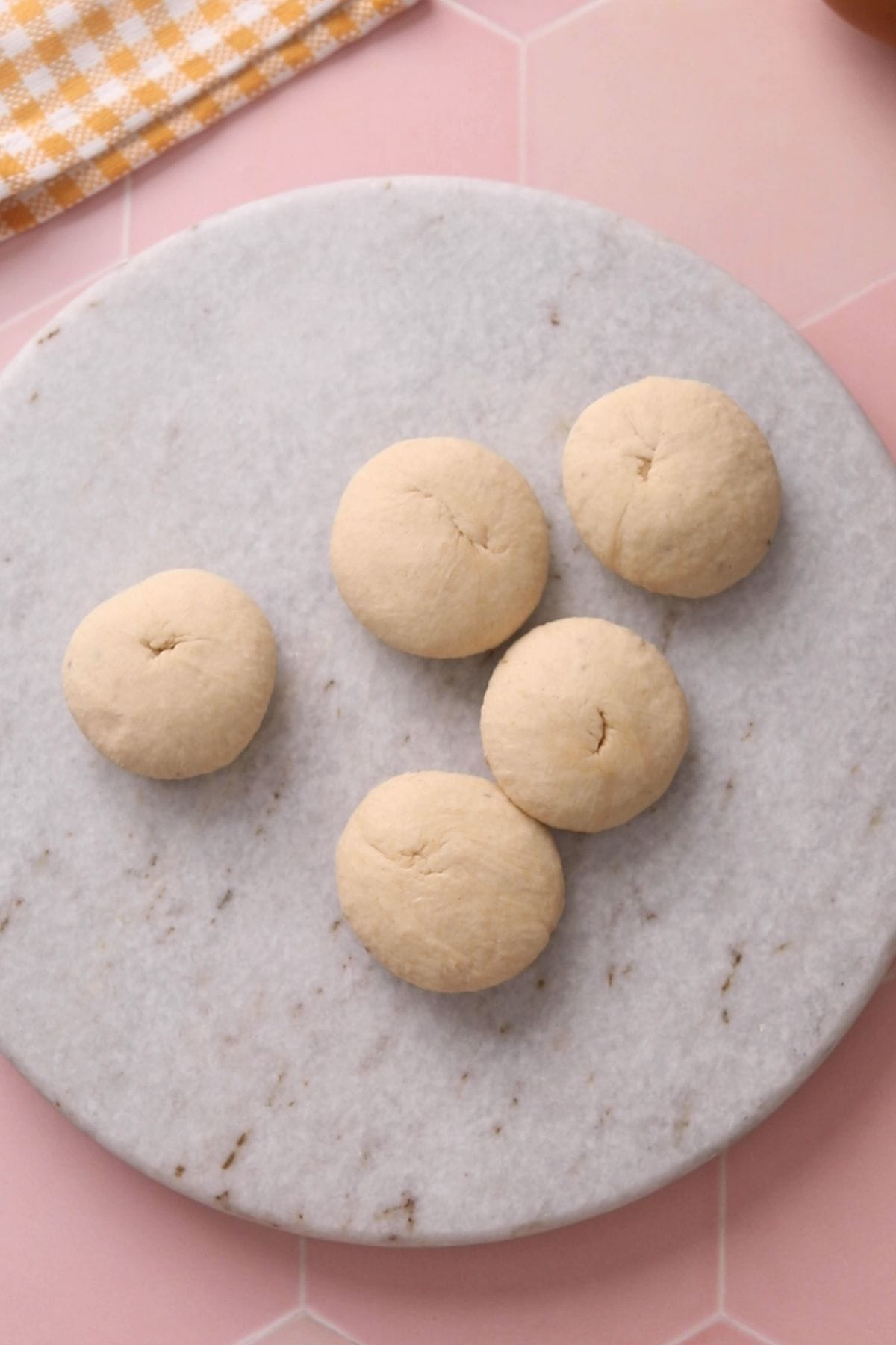 Poori dough balls are smoothened into flat discs.