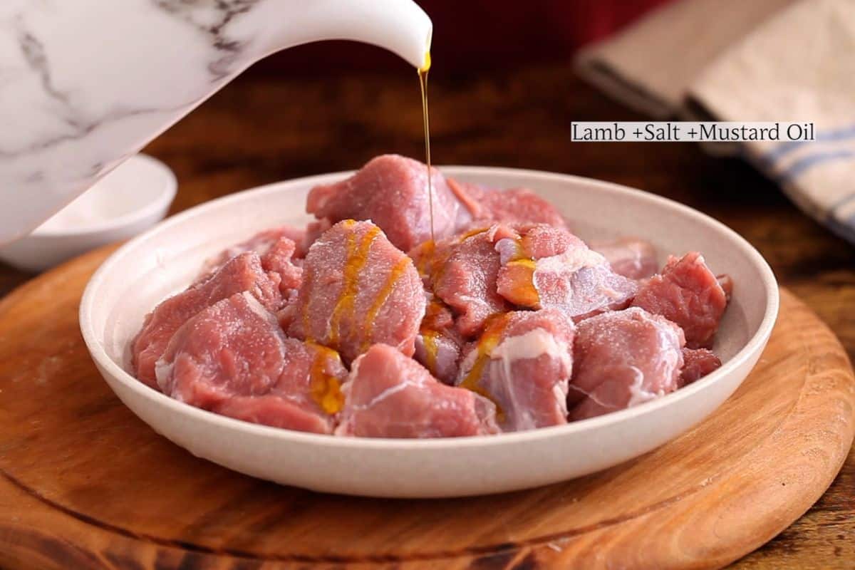 Rubbing lamb with salt and mustard oil.