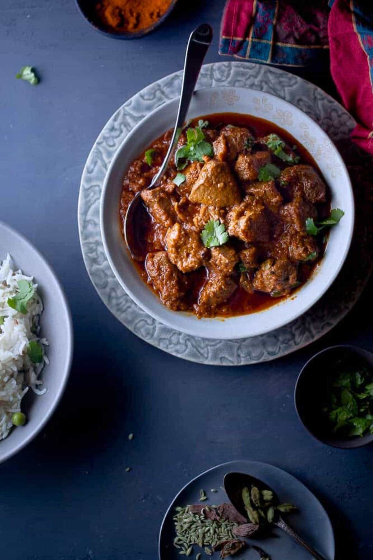 Rogan josh served garnished with cilantro and served with rice on side.