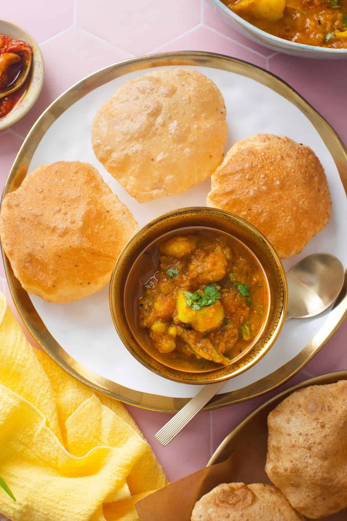 Aloo poori served in a white plate with golden rim. 