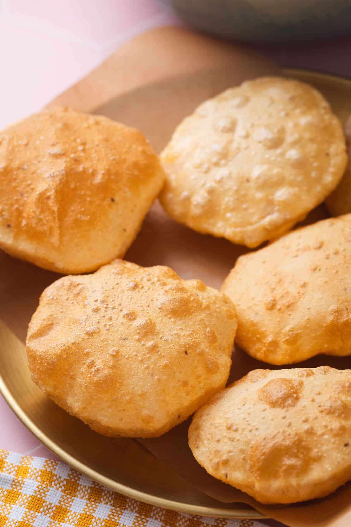 Side view of puffed pooris in a gold plate.