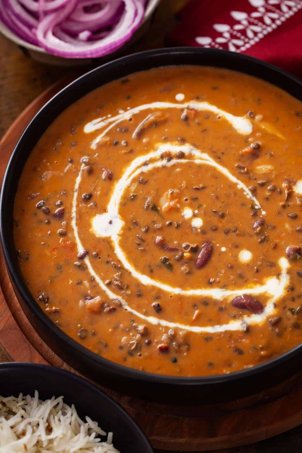 Punjabi Dal Makhani served in a black bowl and drizzled with heavy cream.