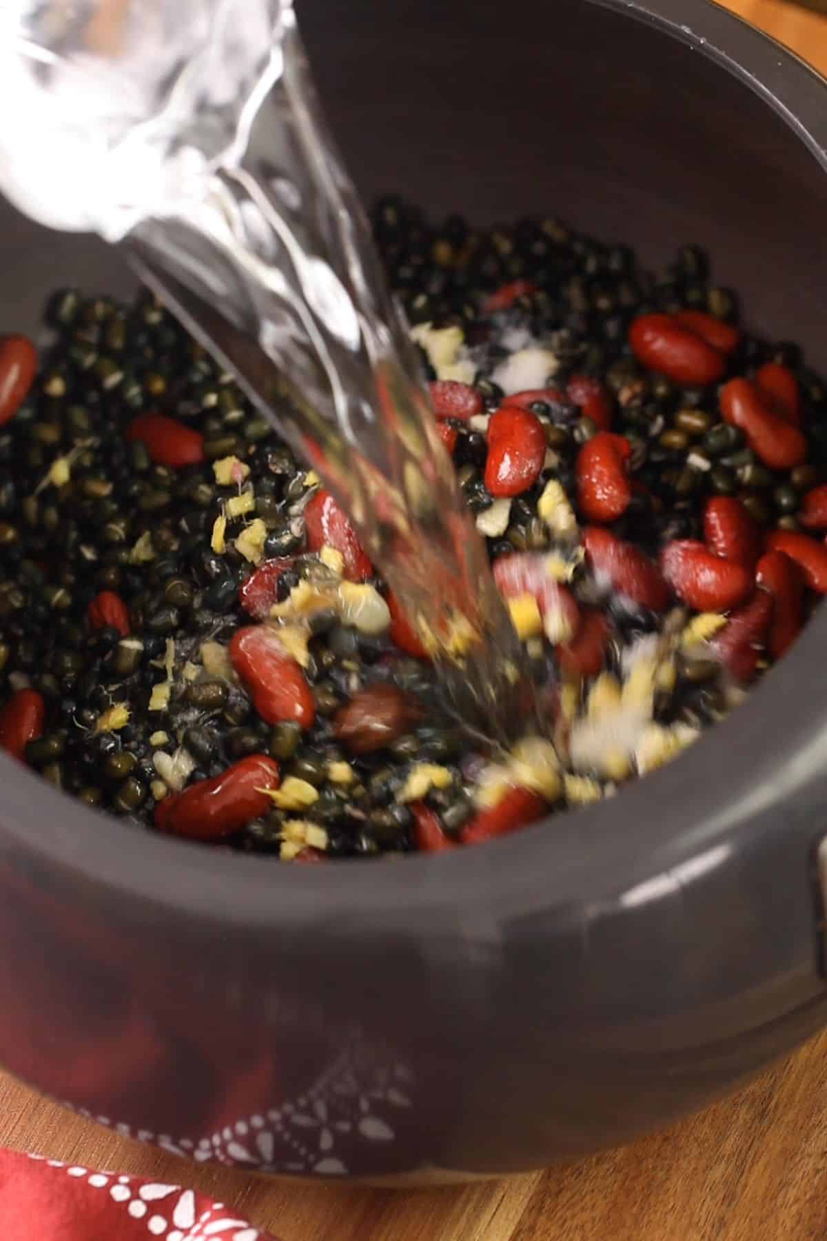 Adding water to soaked lentils for pressure cooking.