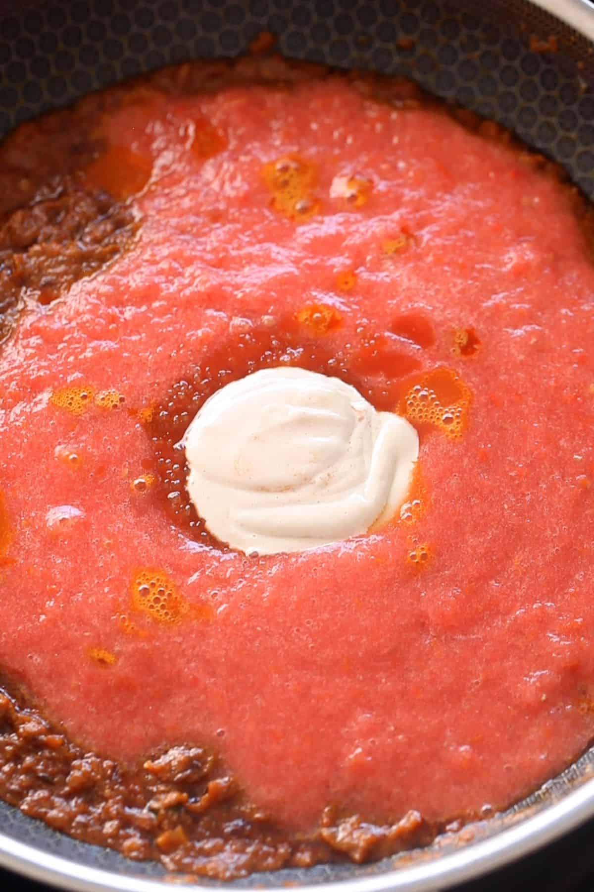 Tomato and cashew paste along with sugar is added next to the masala.