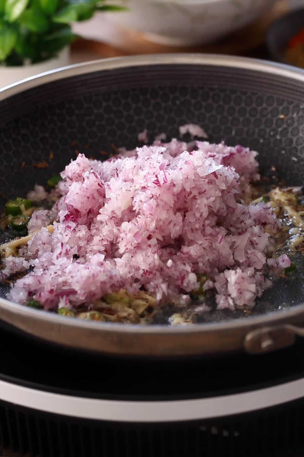 Finely chopped onion is added to the cooking pan.