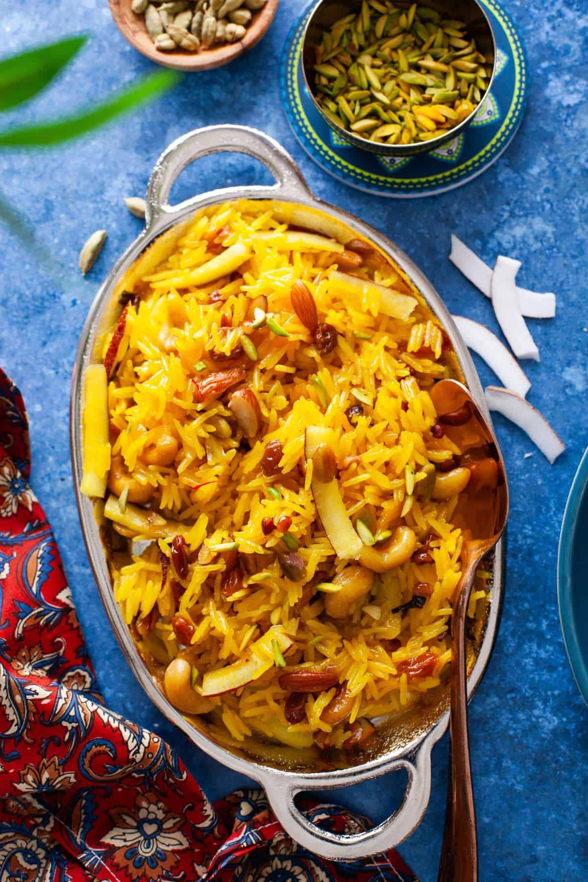 Zarda pulao in a oval steel dish with pistachios and coconut.