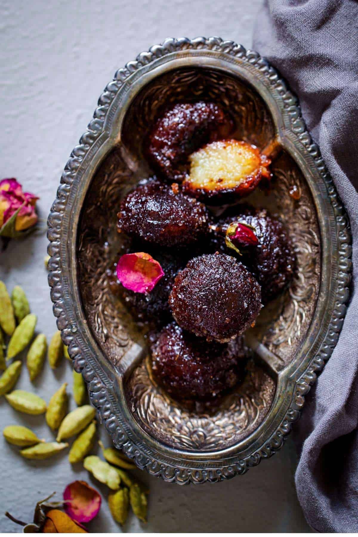 Dry Kala Jamun in a oval silver bowl.