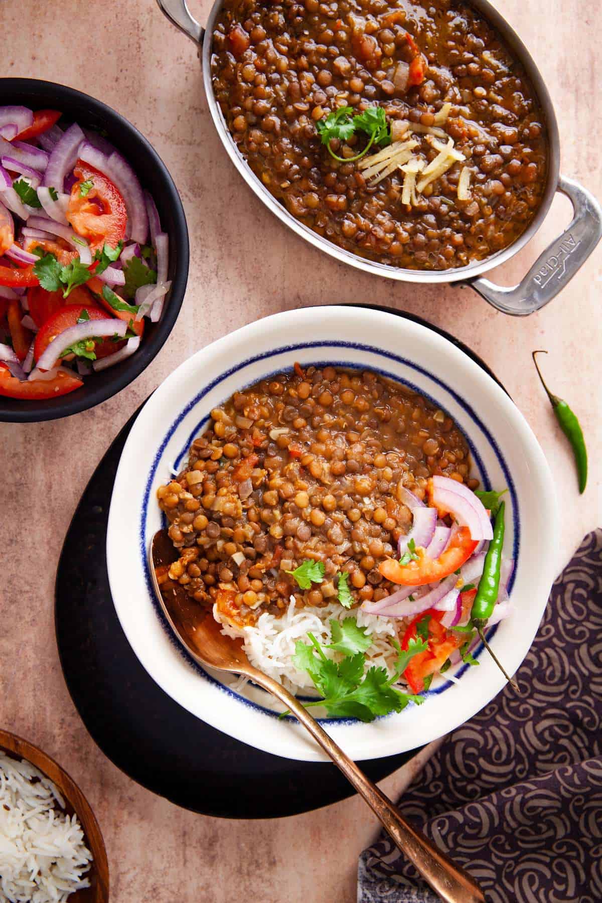 Whole masoor ki dal served over basmati rice with ghee, quick onion tomato salad and cilantro. 