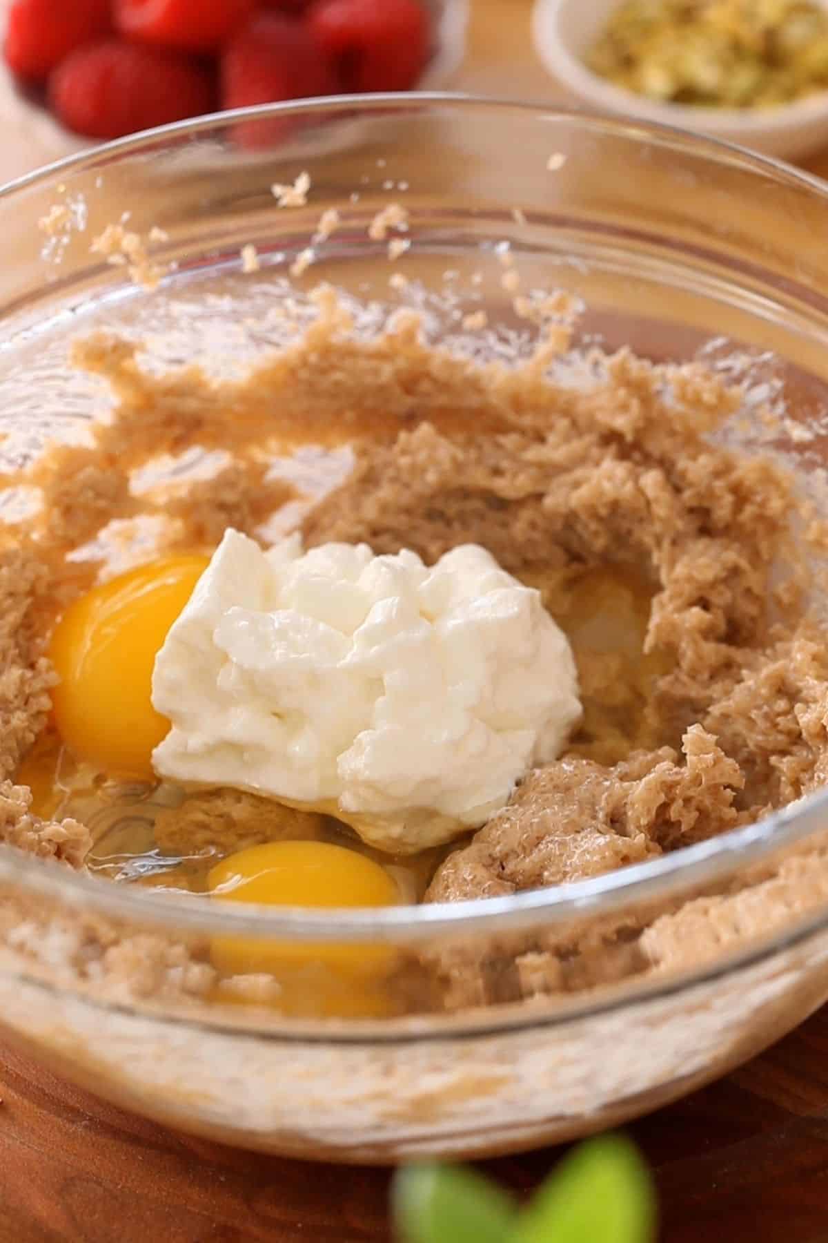 Wet ingredients added to a large mixing bowl made of glass.