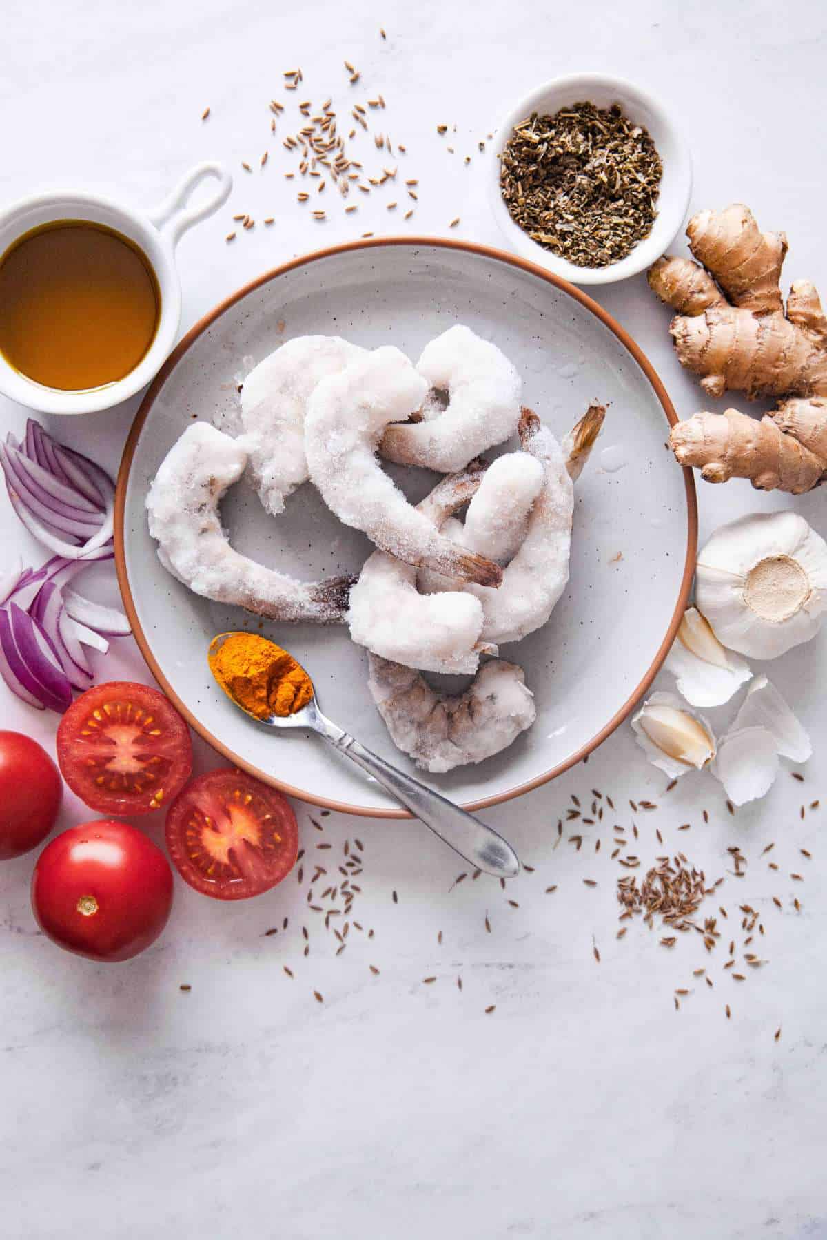 Ingredients needed to make shrimp curry on a white marble background.