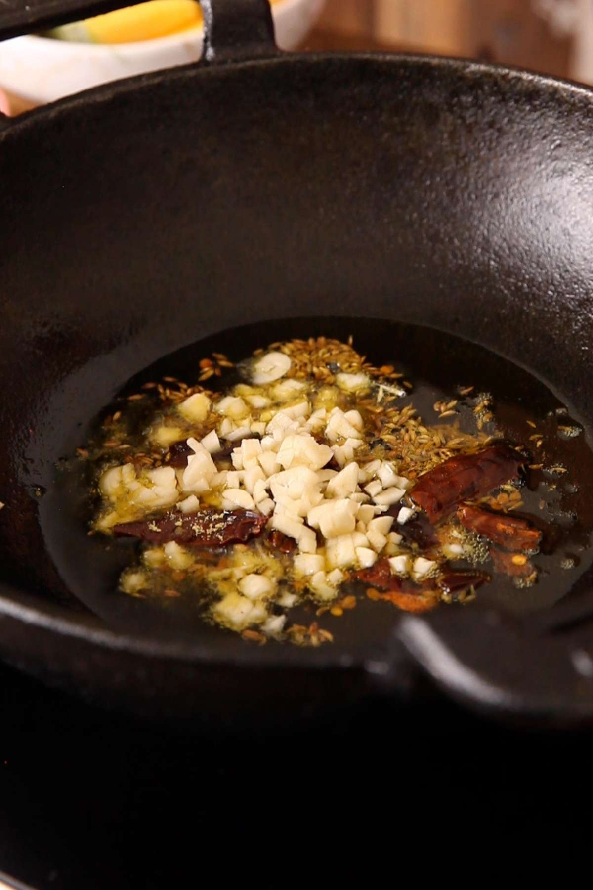 Temper hot mustard oil with garlic & whole spices.