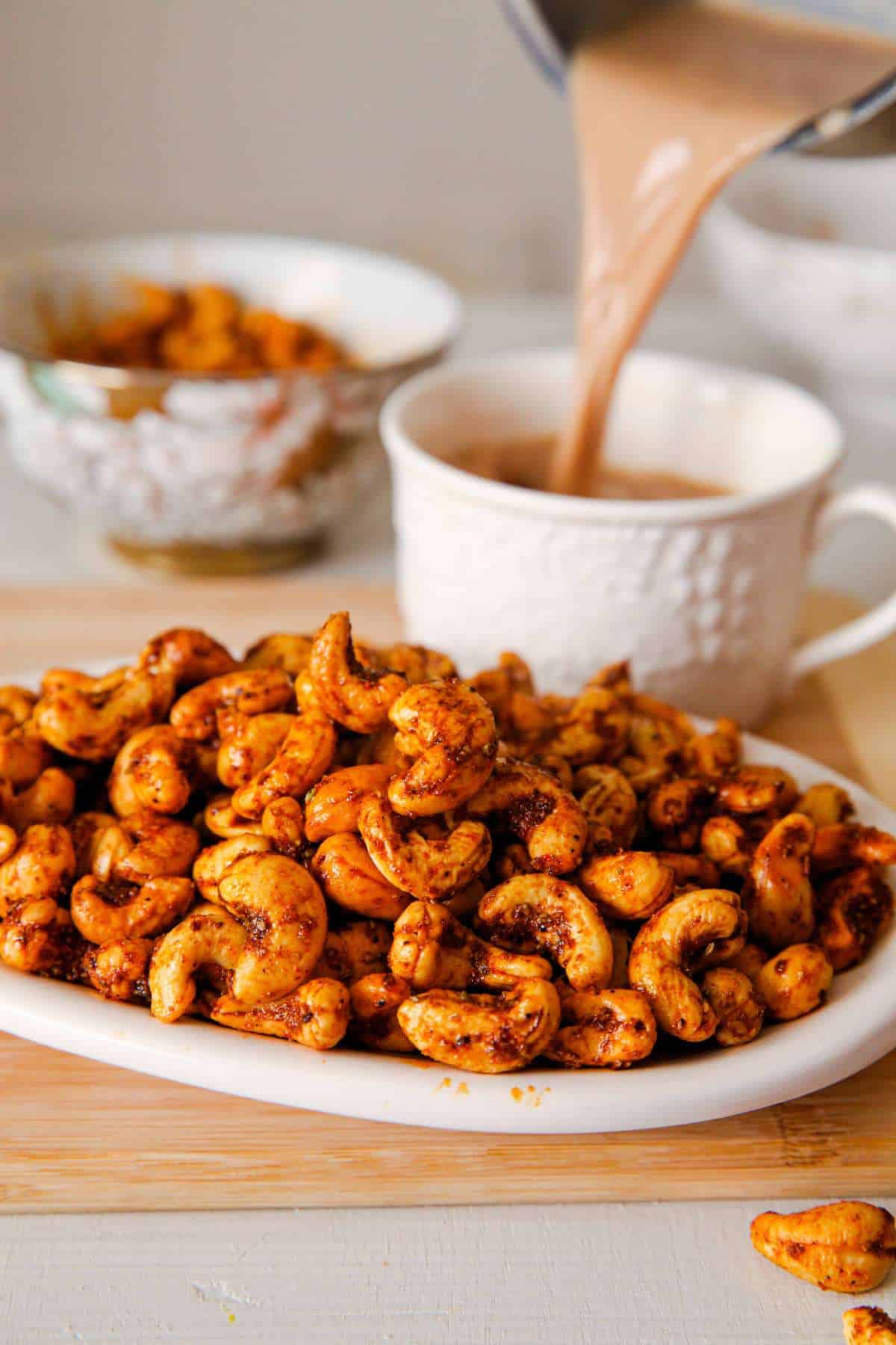 Spicy Cashews with a chai pour in the background.