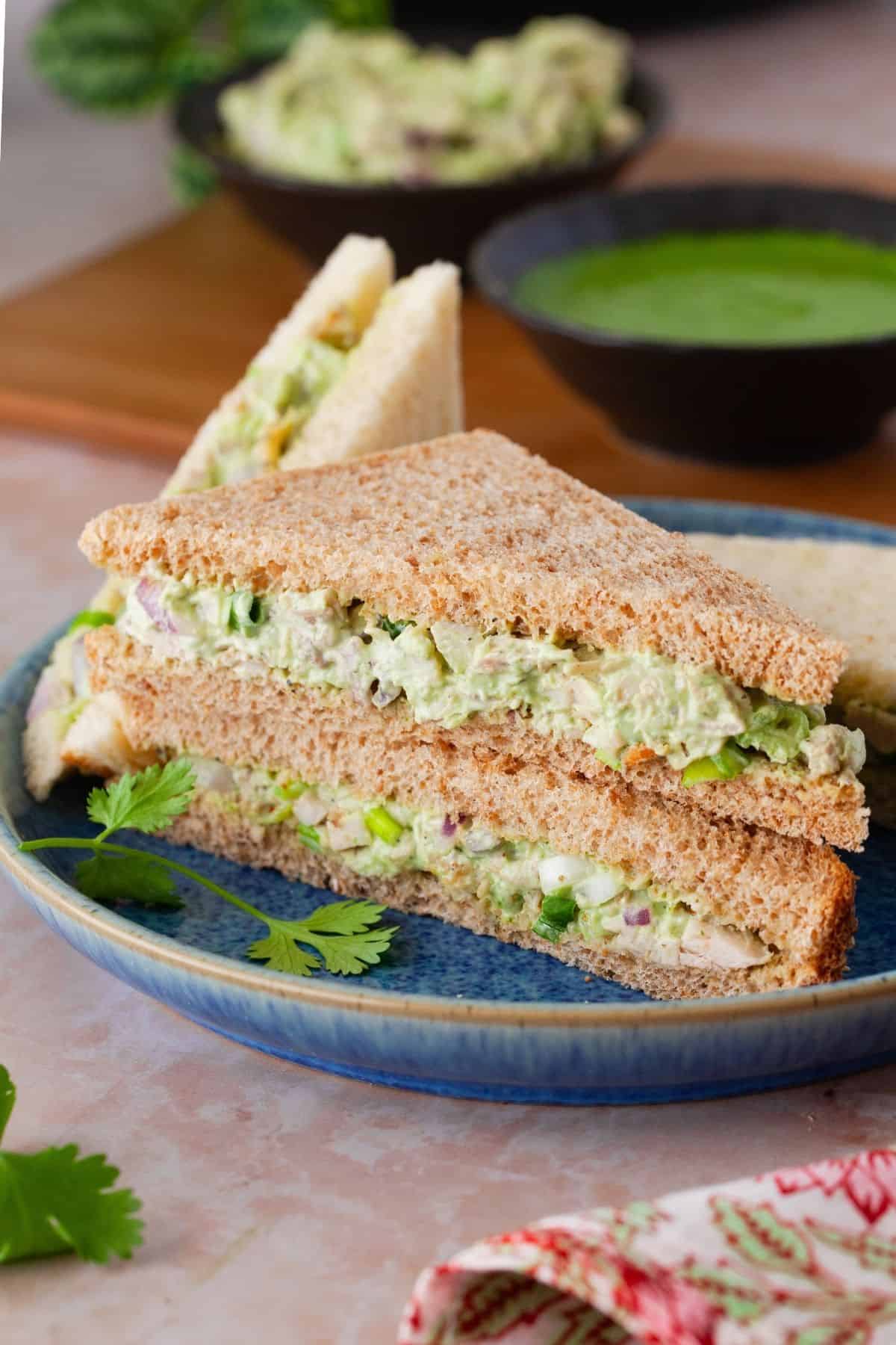 Chicken chutney sandwich traingles placed on a blue plate.