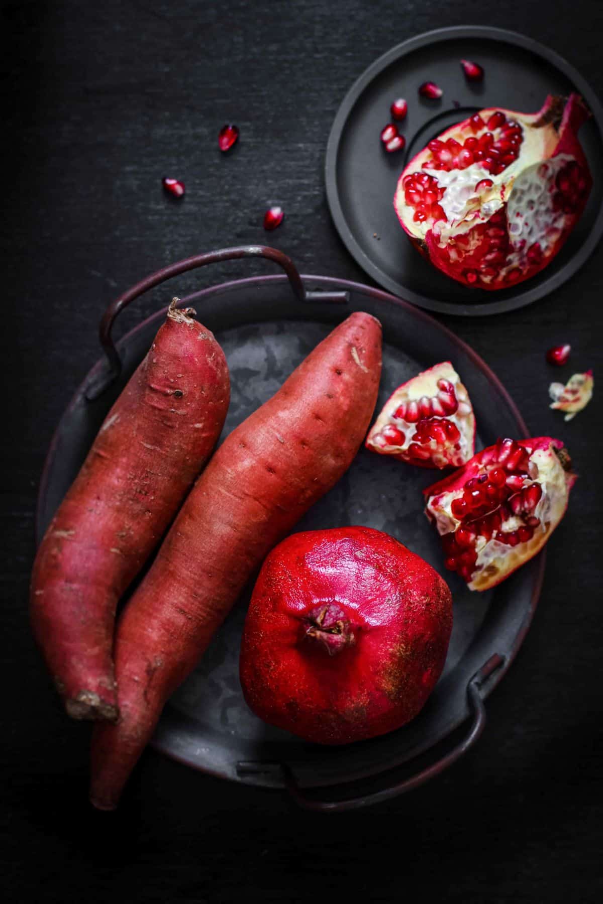 Sweet potato and pomegranate on a black background.