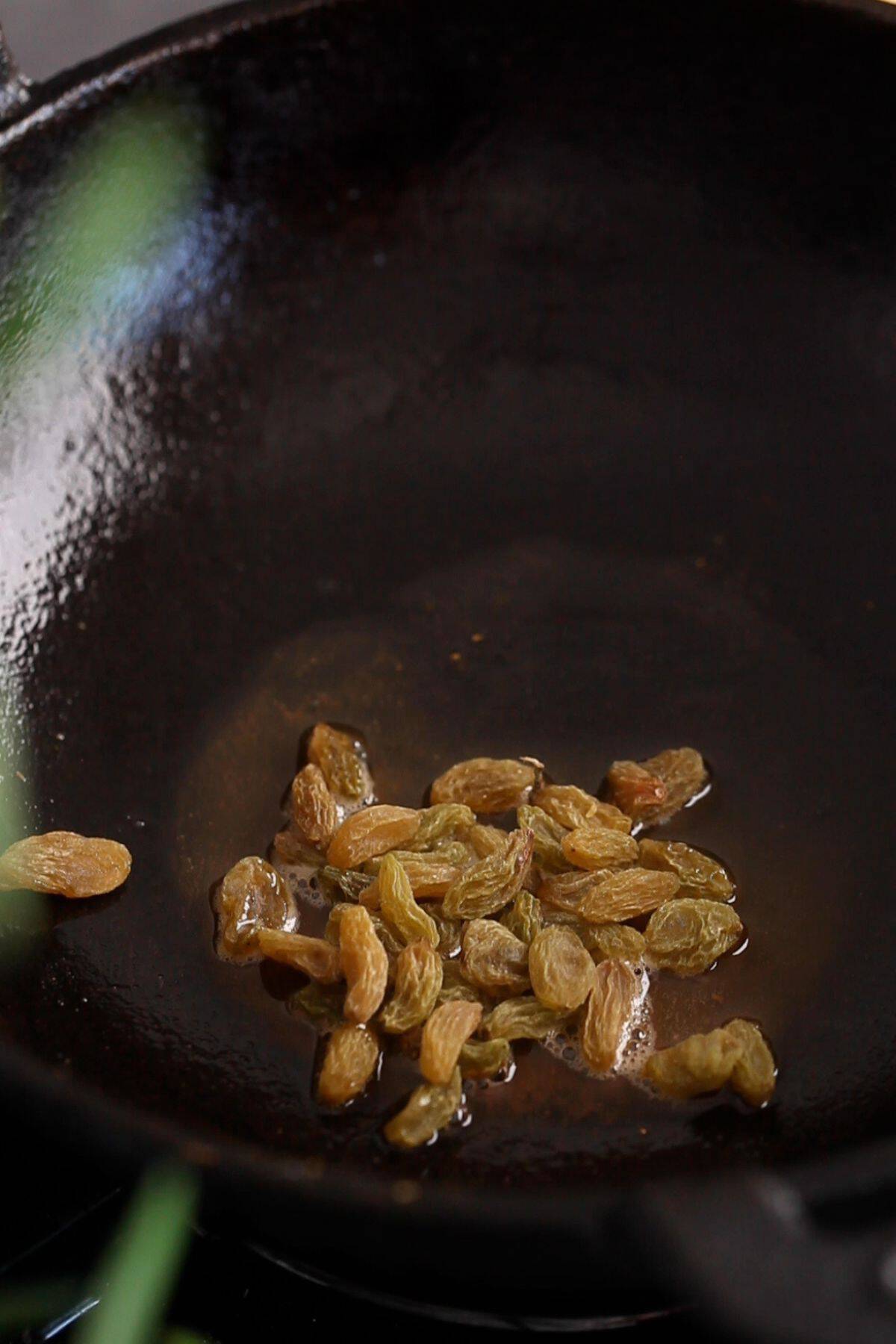 Roasting golden riasins in ghee.