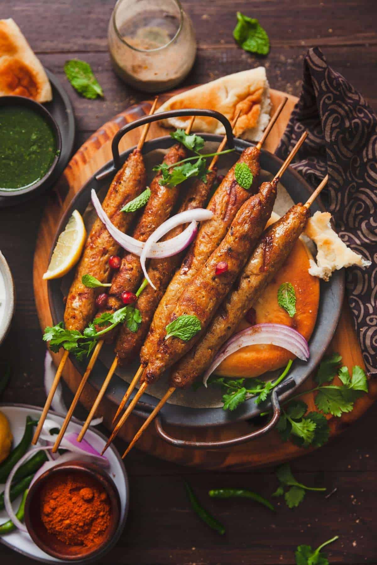 Chicken Seekh Kebab On Skewers with flatbread, green chutney, onions and naan