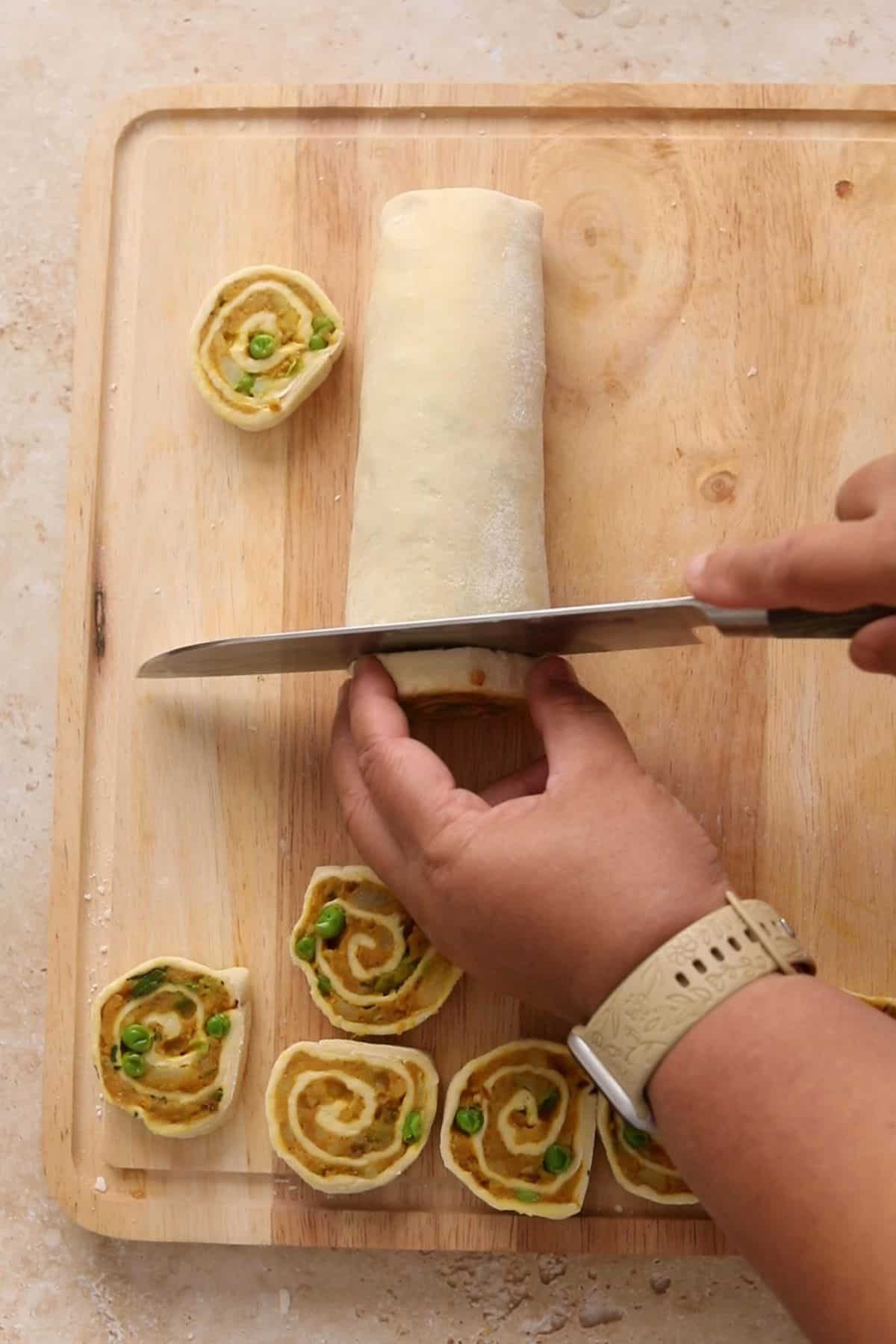 Samosa roll is being cut into pinwheels.