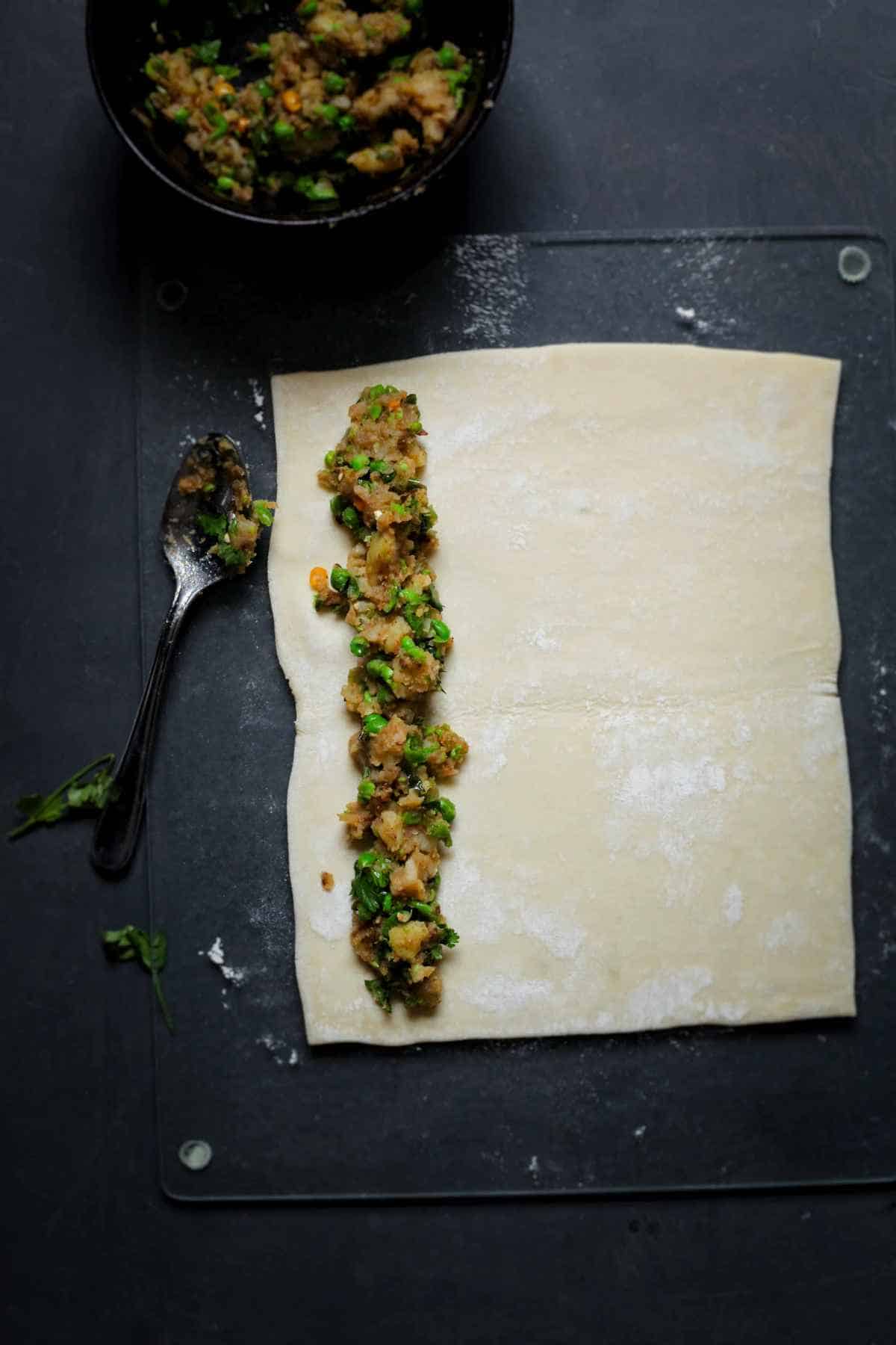 Samosa filling placed in the center of puff pastry.