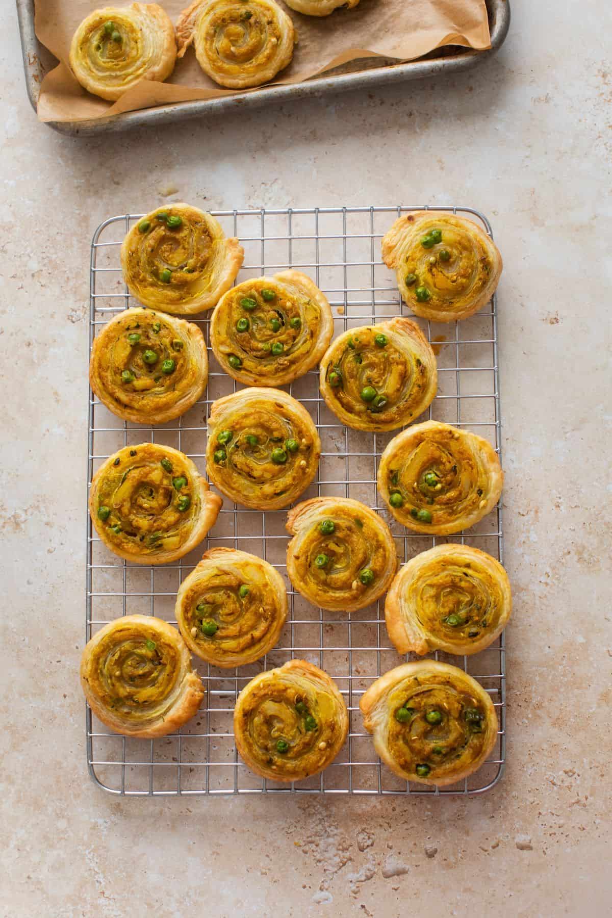Baked samosa pinwheels placed on a steel wire rack.