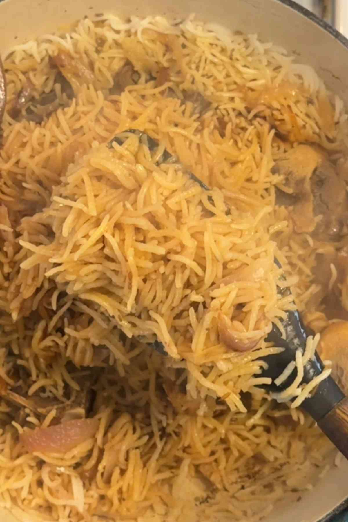 Fluffing mutton yakhni pulao with soft spatula.