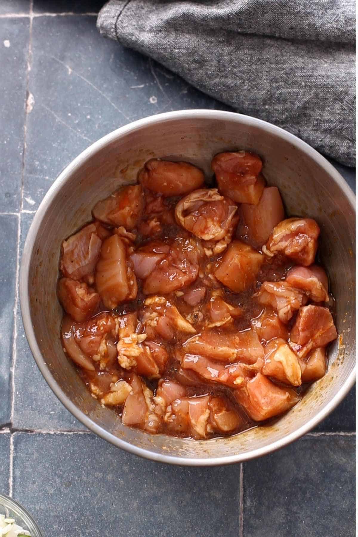 Marinated chicken in a stell mixing bowl.