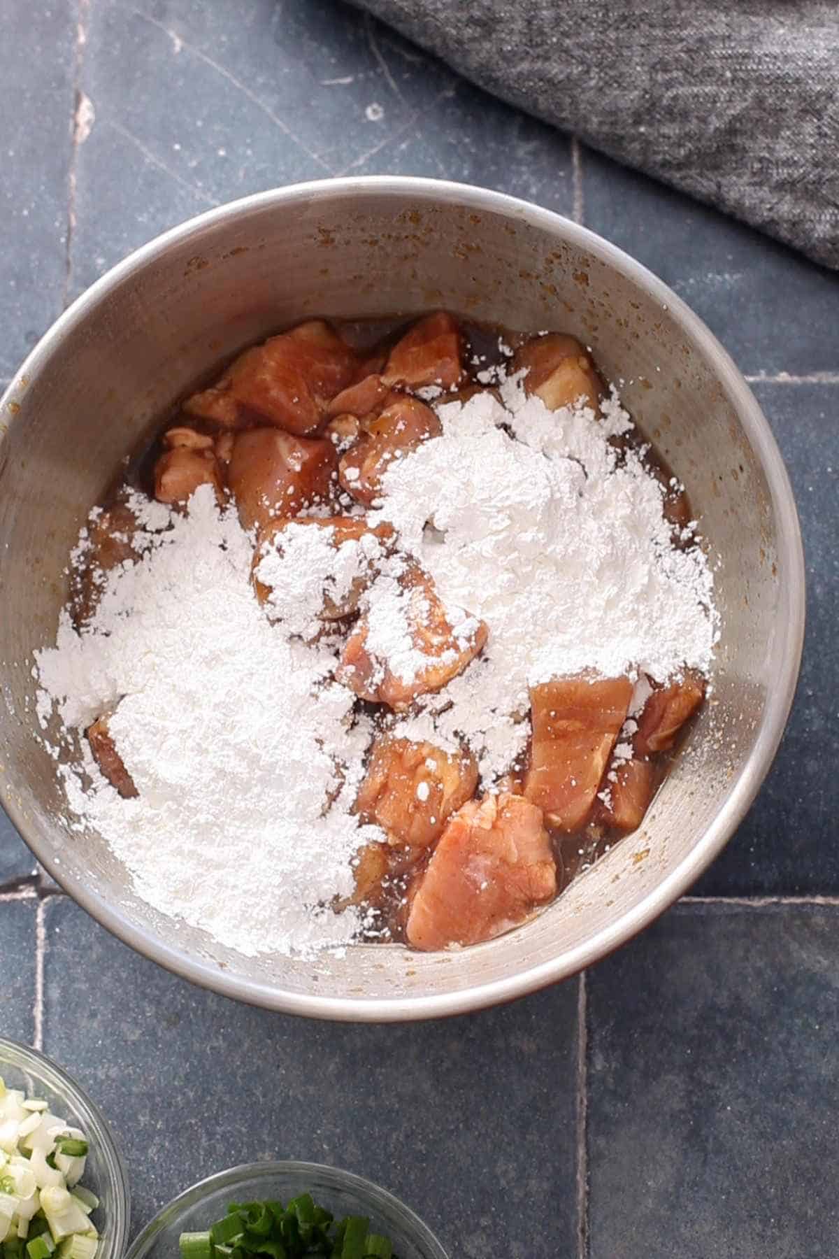 Corn starch added to marinated chicken.