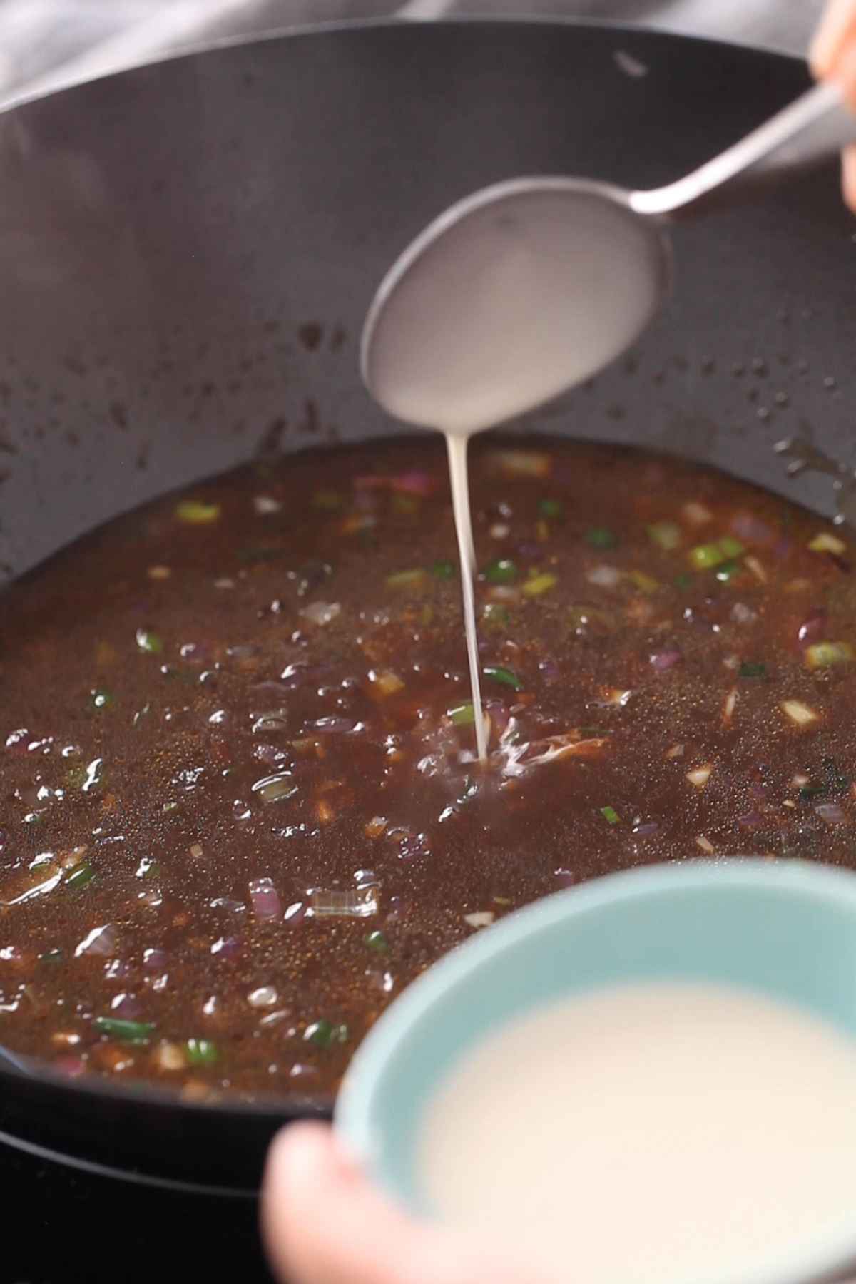 Adding corn starch slurry to the manchurian sauce.