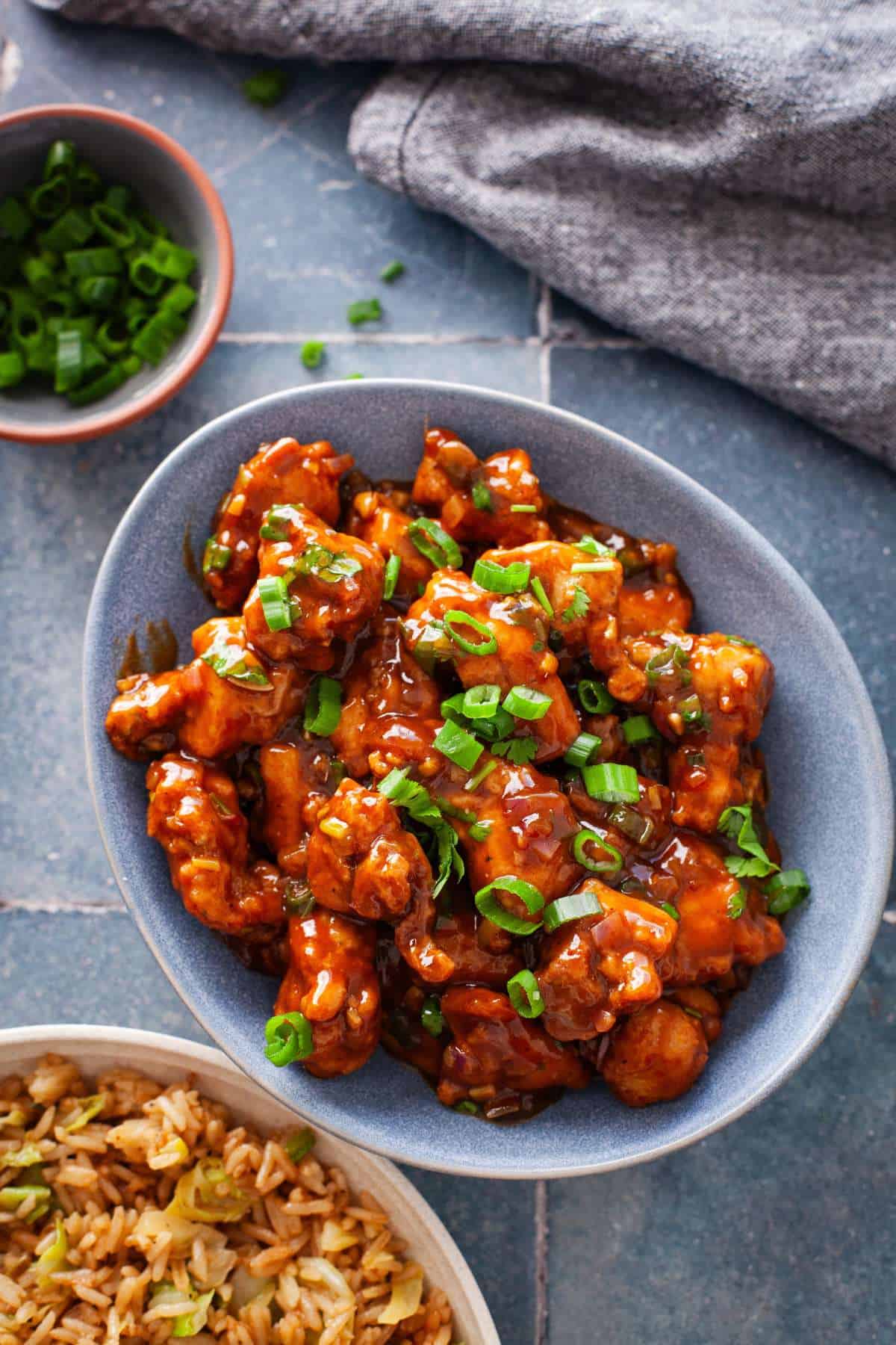 Chicken Manchurian with crispy chicken in an oval blue bowl.