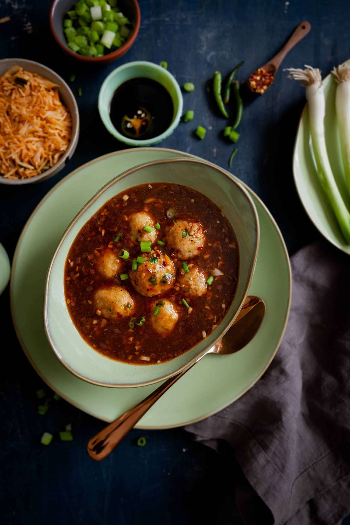 Chicken Manchurian with chicken meatballs in a oval green bowl.