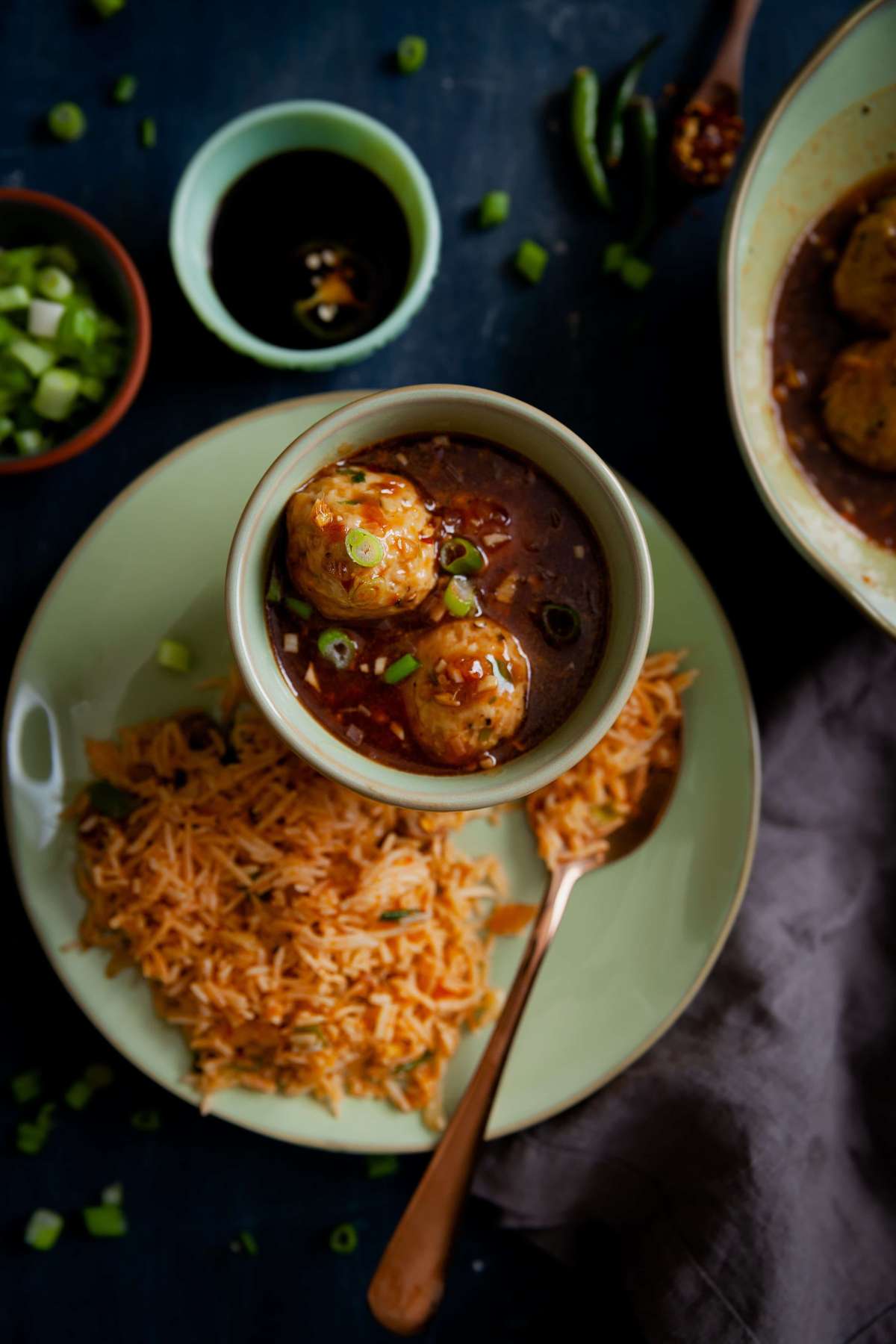 Chicken manchurian served with fried rice in a green plate.