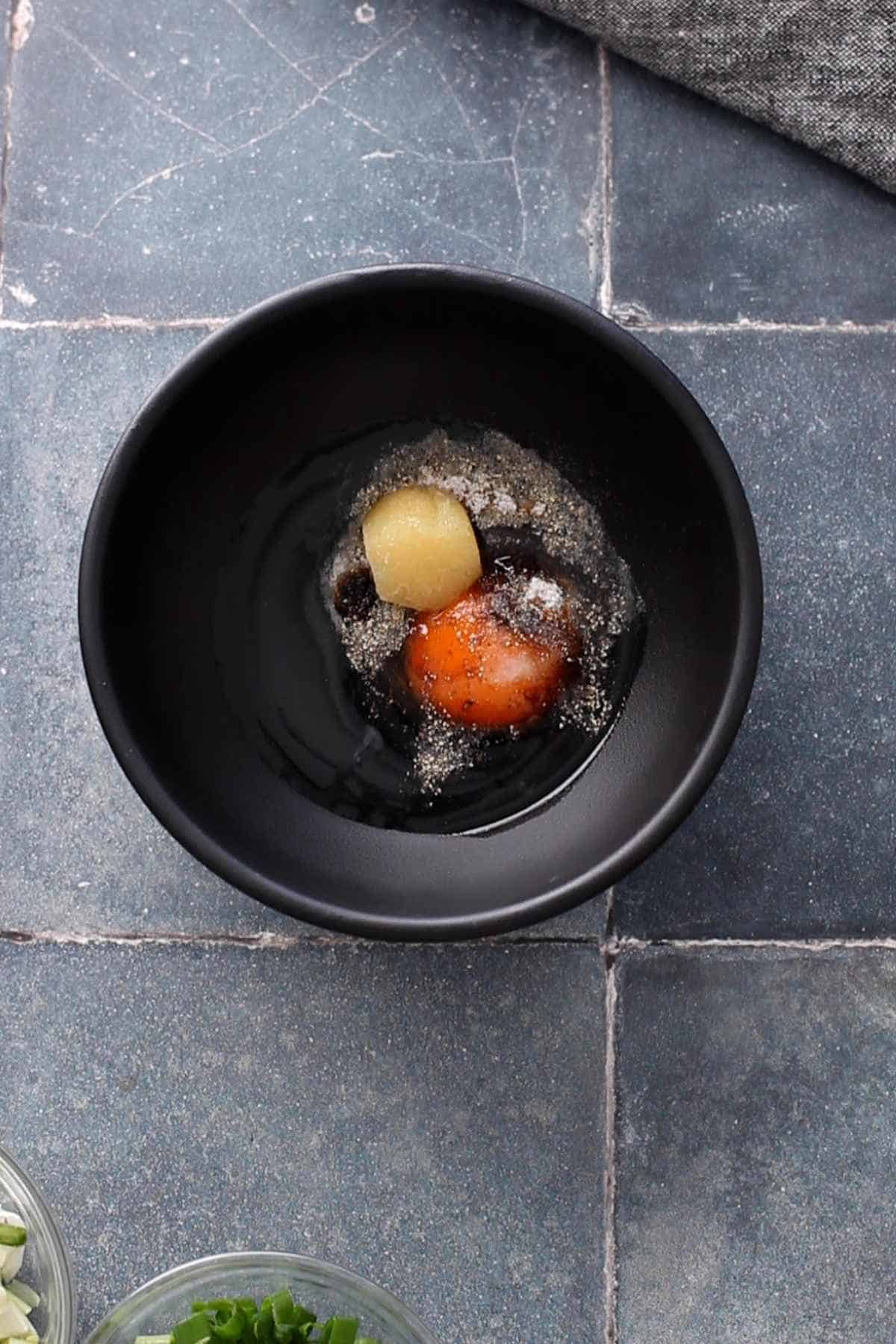 Black bowl with chicken marinade ingredients.