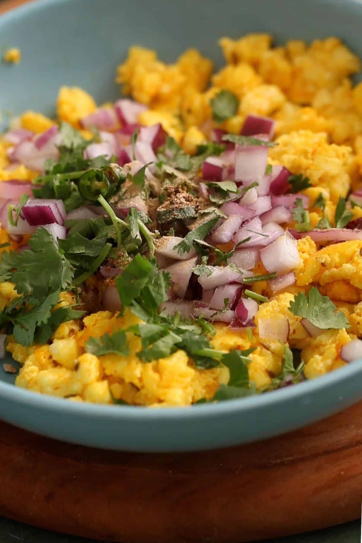 Onion and cilantro is added to paneer along with spices.