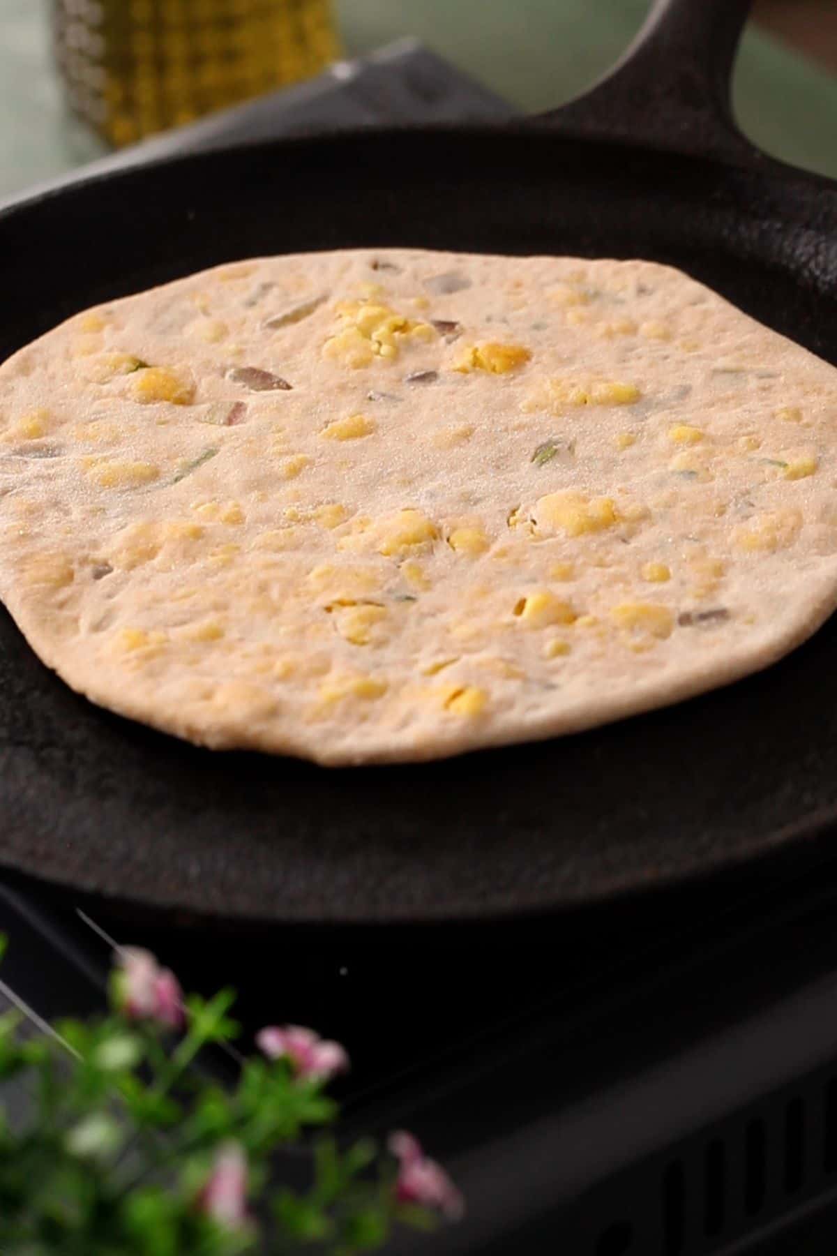 paneer paratha is placed on a cast iron griddle.