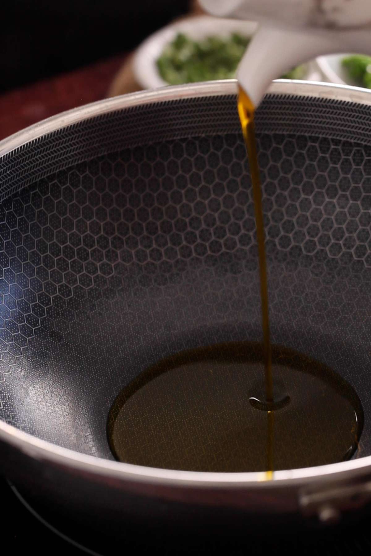 Adding mustard oil to a wok pan. 