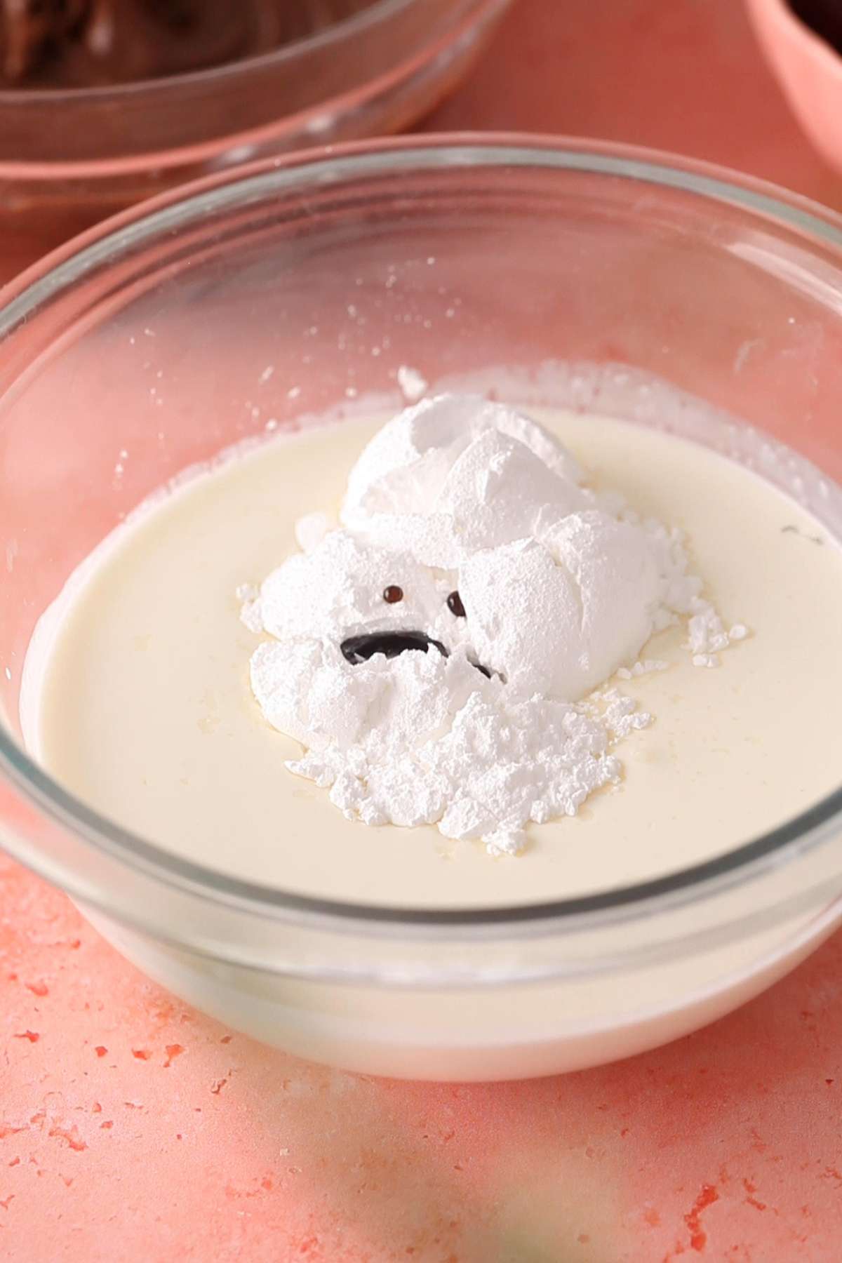 Heavy whipping cream, sugar and vanilla in a glass bowl.