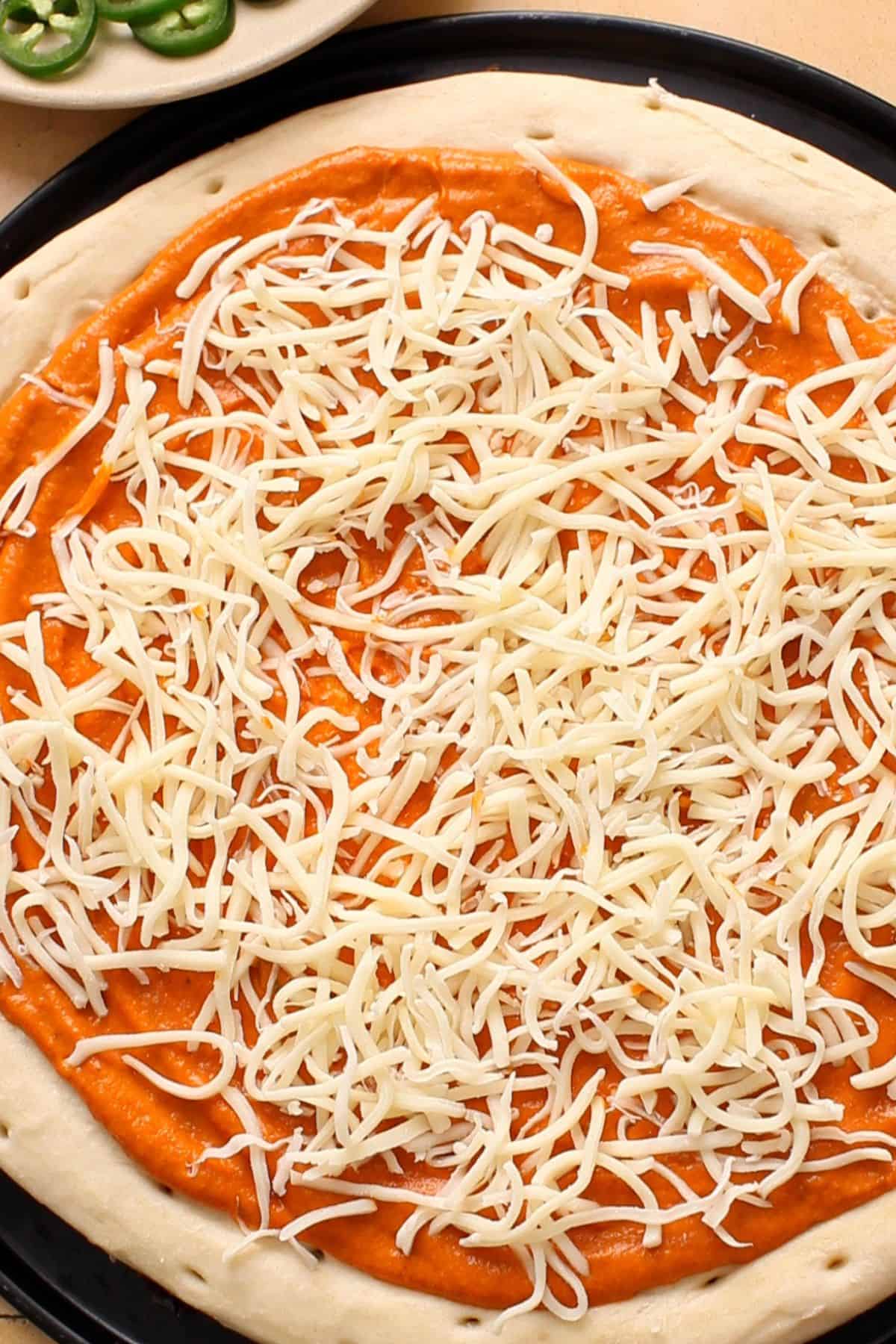 Shredded cheese is added on the pizza crust.