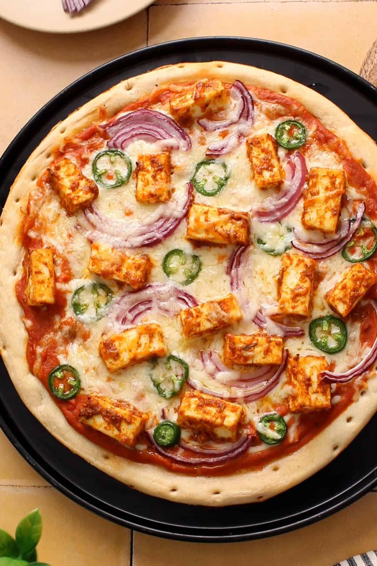 Baked makhani paneer pizza with gooey cheese.